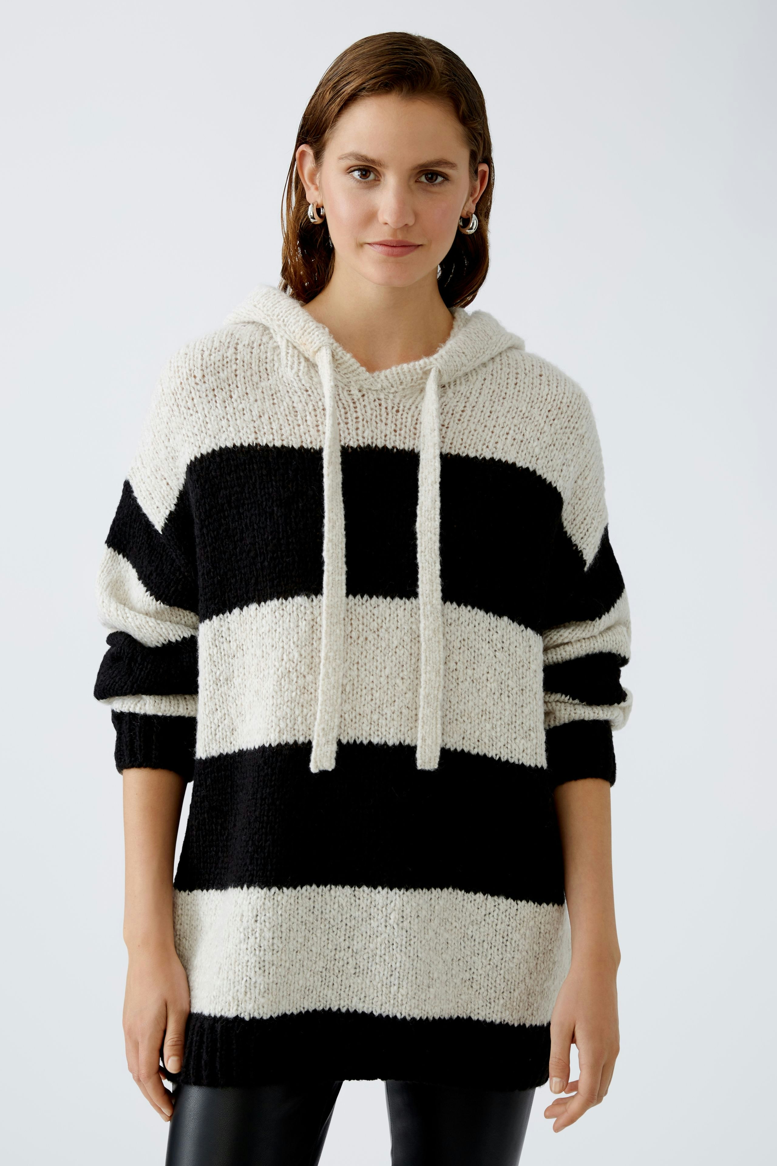Stylish women's hoodie: A woman in a black and white striped pullover with a relaxed fit.
