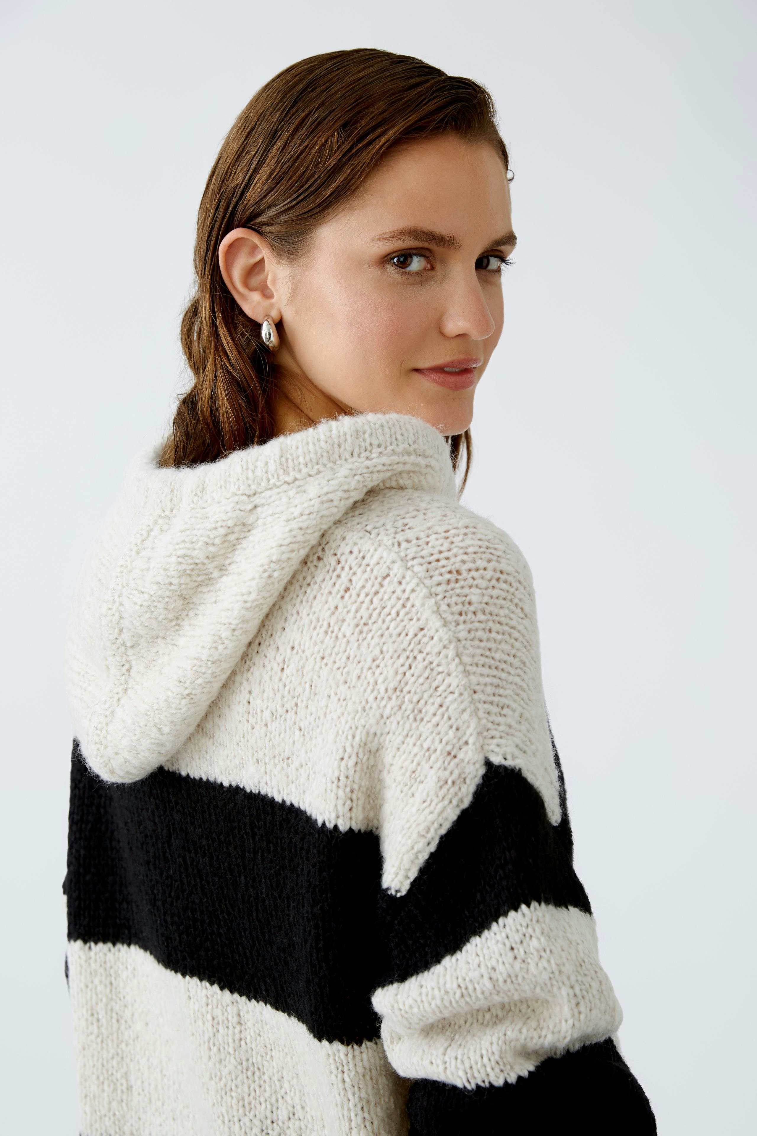 Stylish women's hoodie: A woman in a cozy striped pullover with a hood, exuding casual elegance.