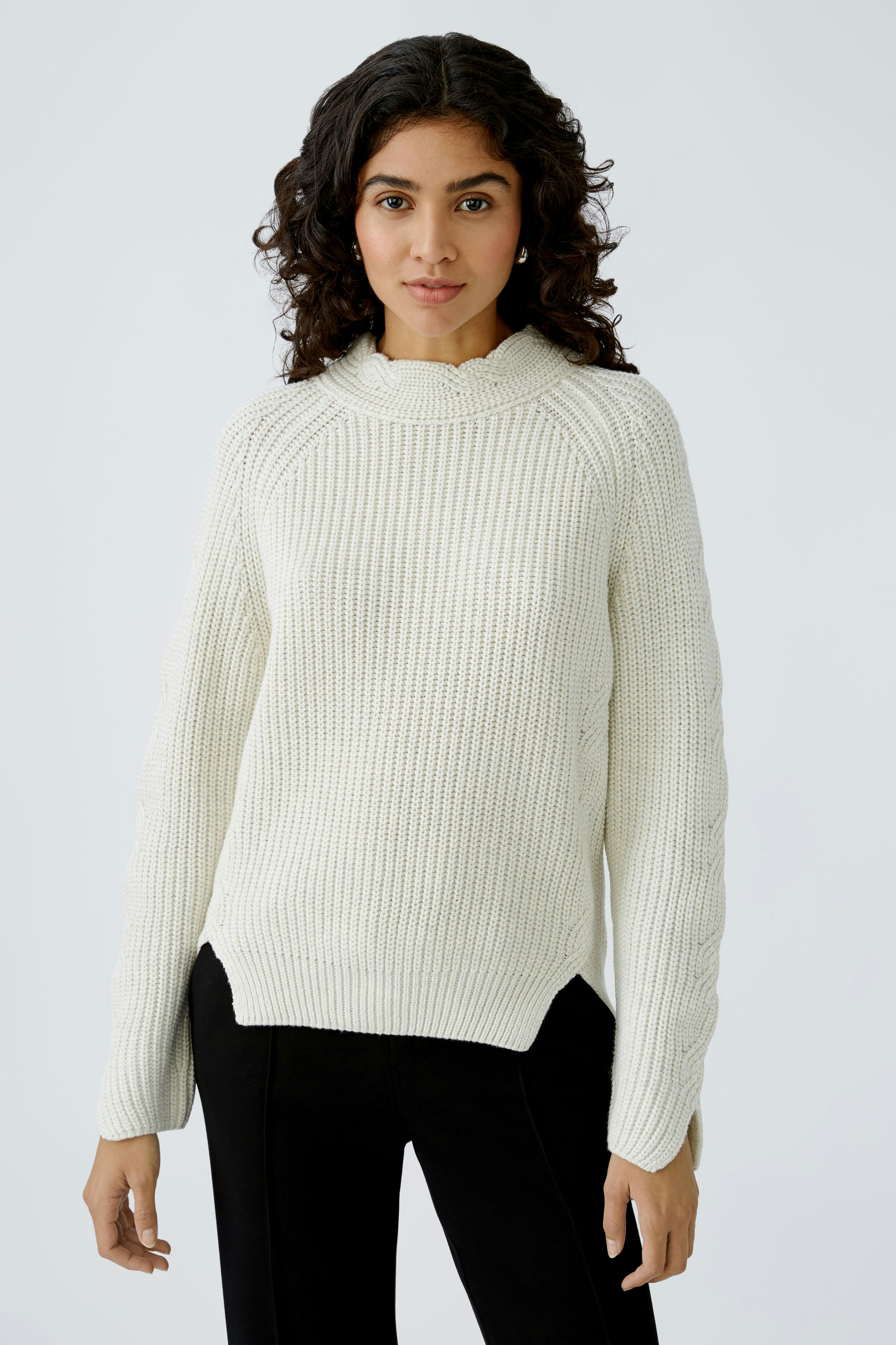 Stylish women's pullover: A woman in a cozy white knit pullover with a relaxed fit.
