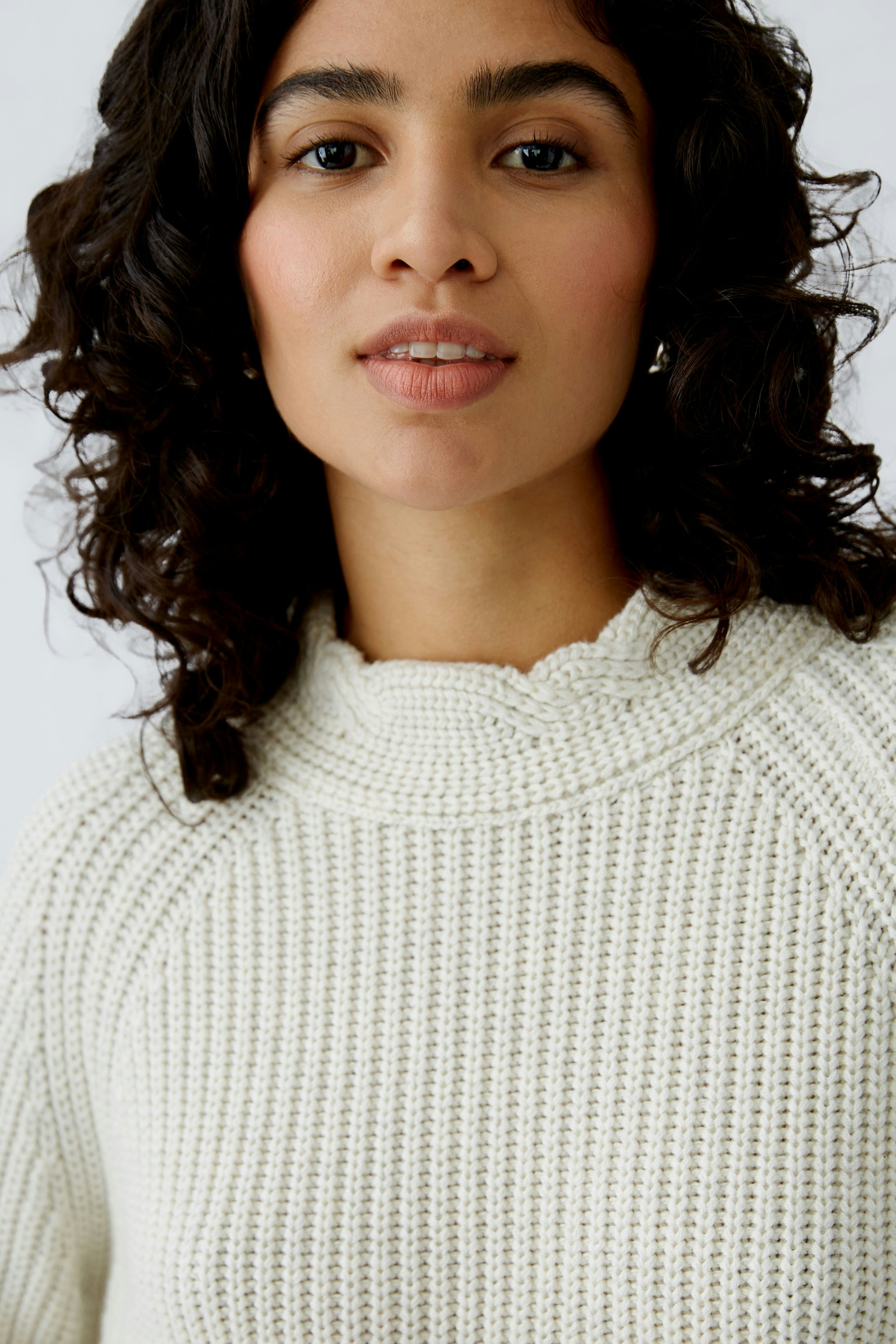 Stylish women's pullover: A woman in a cozy cream knit pullover with a scalloped neckline.