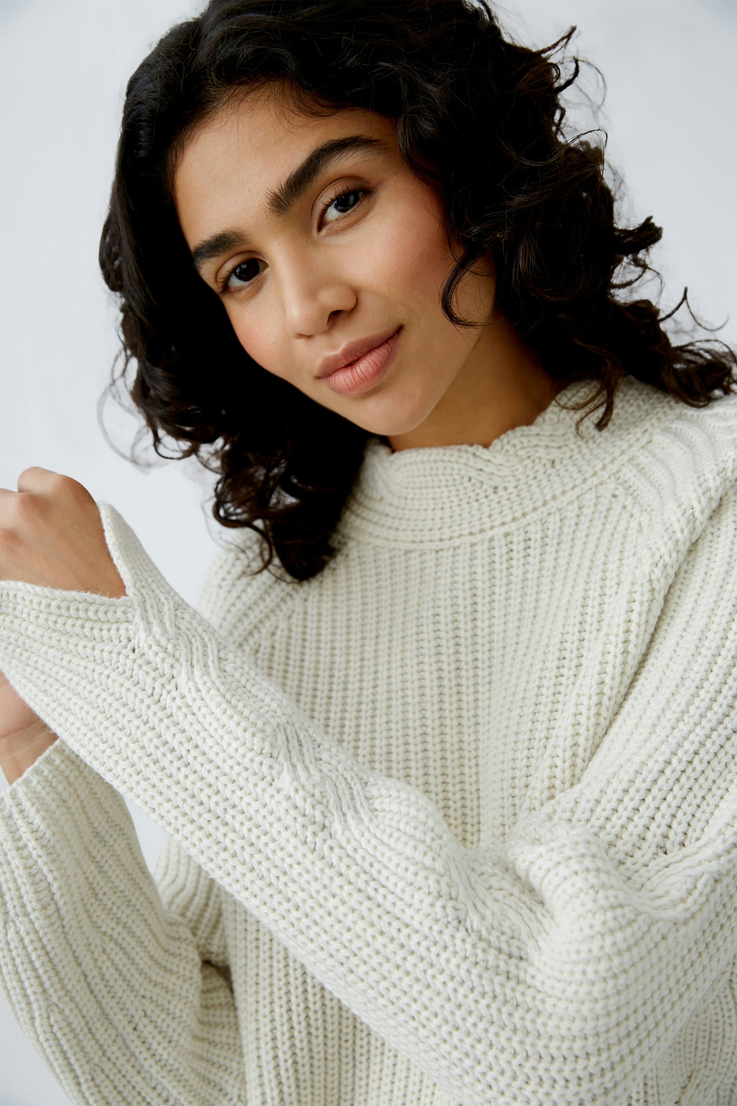 Stylish women's pullover: A woman in a cozy cream knit pullover with a relaxed fit.
