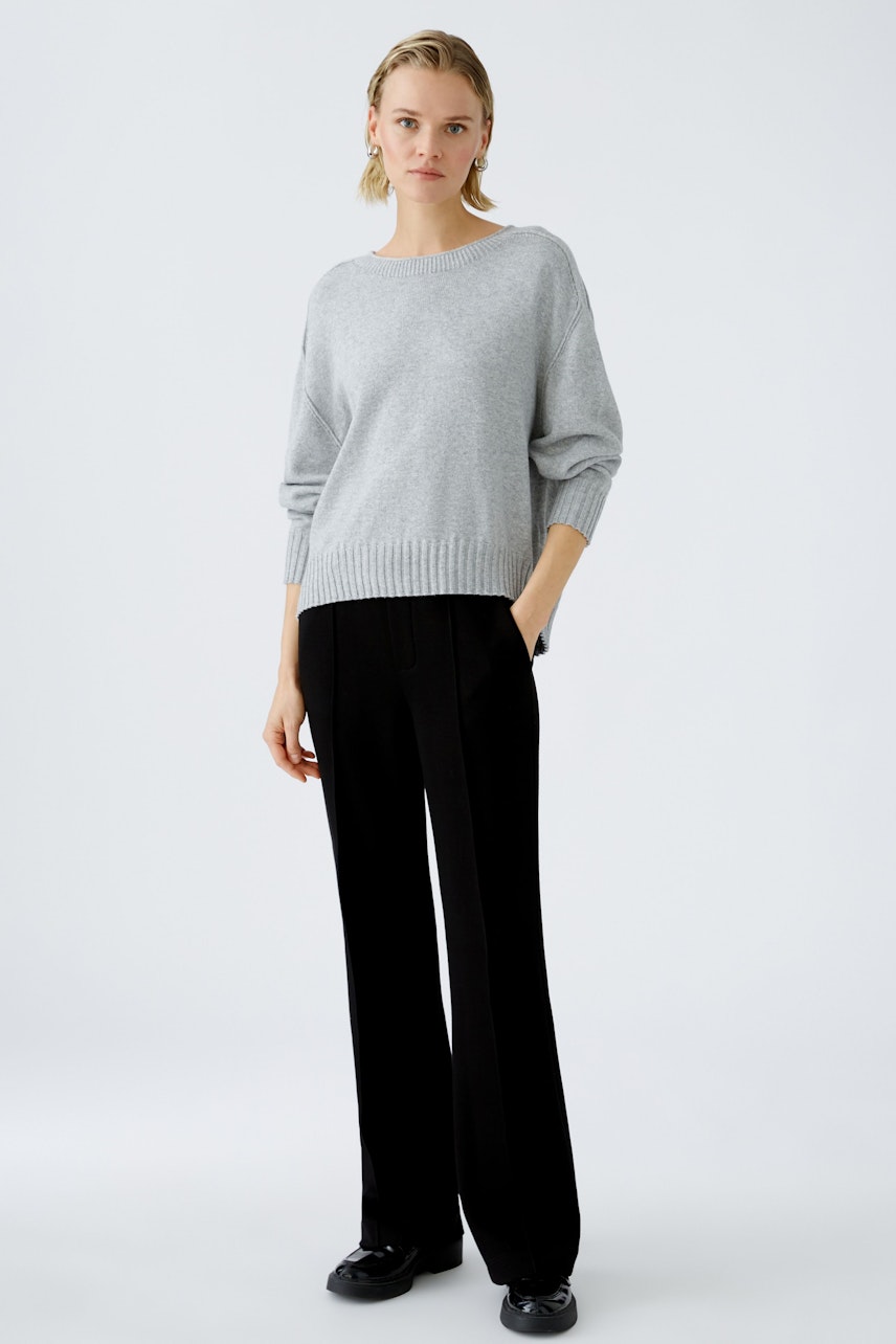 Stylish women's pullover: A woman in a light gray pullover paired with black trousers.