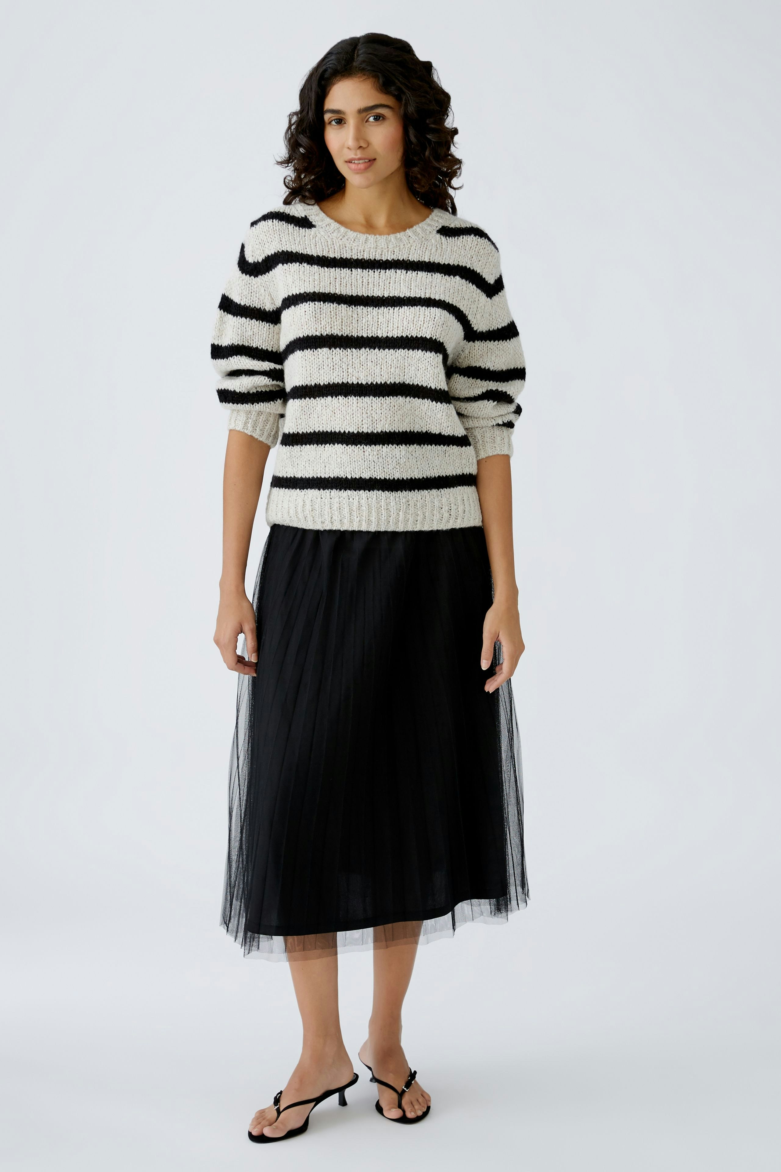 Damen-Pullover: Frau in gestreiftem, lässigem Strickpullover mit schwarzem Rock und Sandalen.