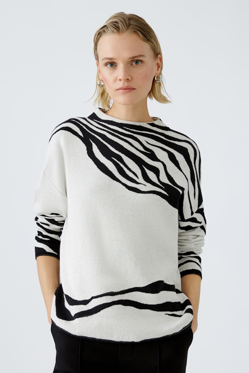 Stylish women's pullover: A woman in a white pullover with black zebra stripes, exuding confidence.