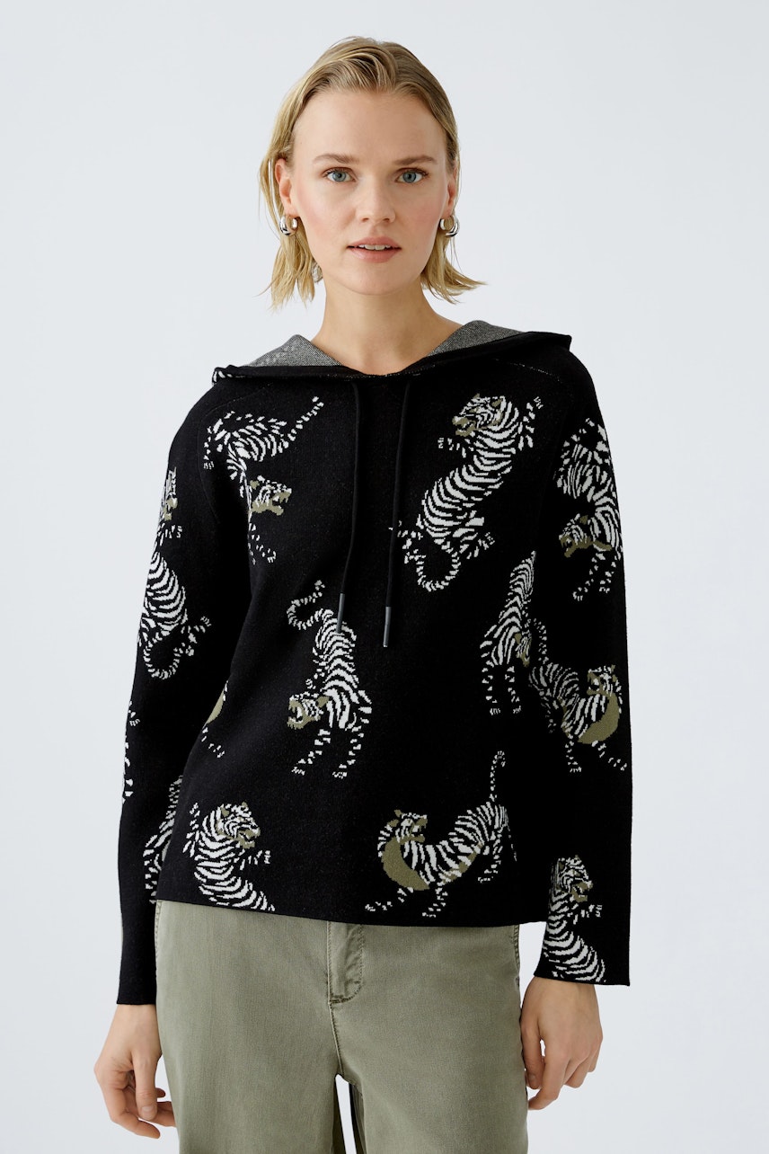 Stylish women's hoodie: A woman in a black pullover with tiger print, exuding confidence.