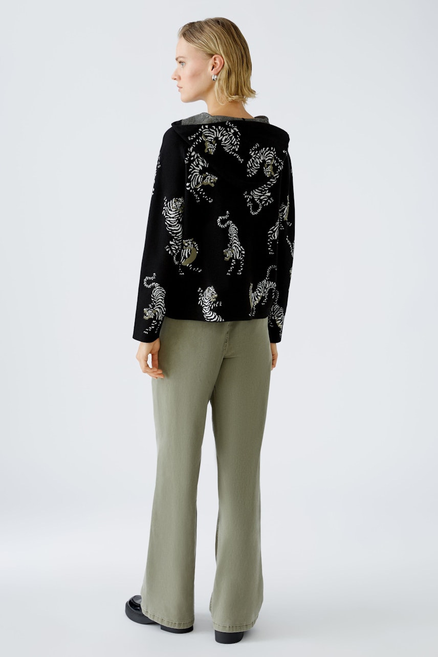 Stylish women's hoodie: A woman in a black pullover with a playful animal print, paired with relaxed pants.