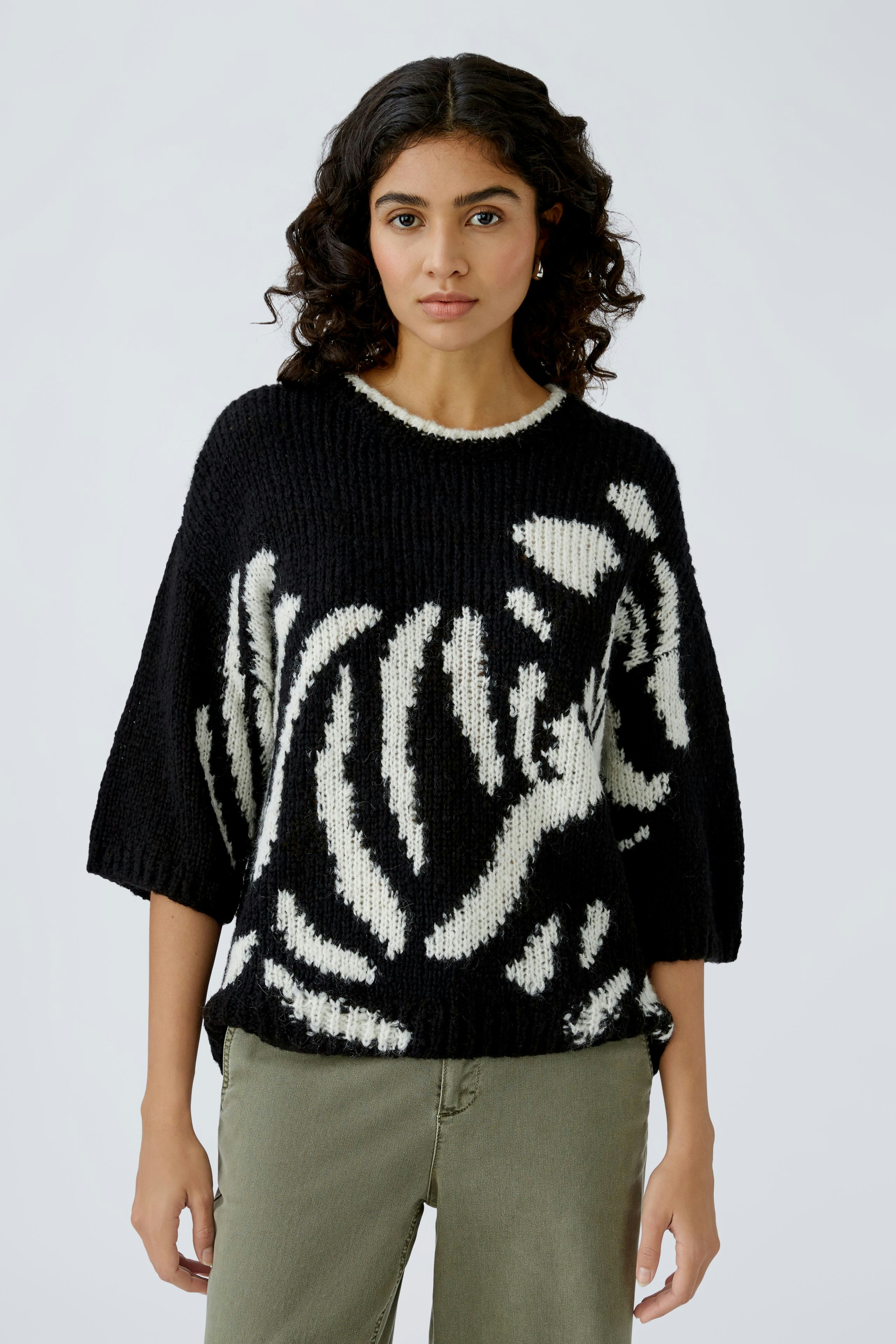 Damen-Pullover: Frau in schwarzem Pullover mit weißem Muster und lässiger Passform.