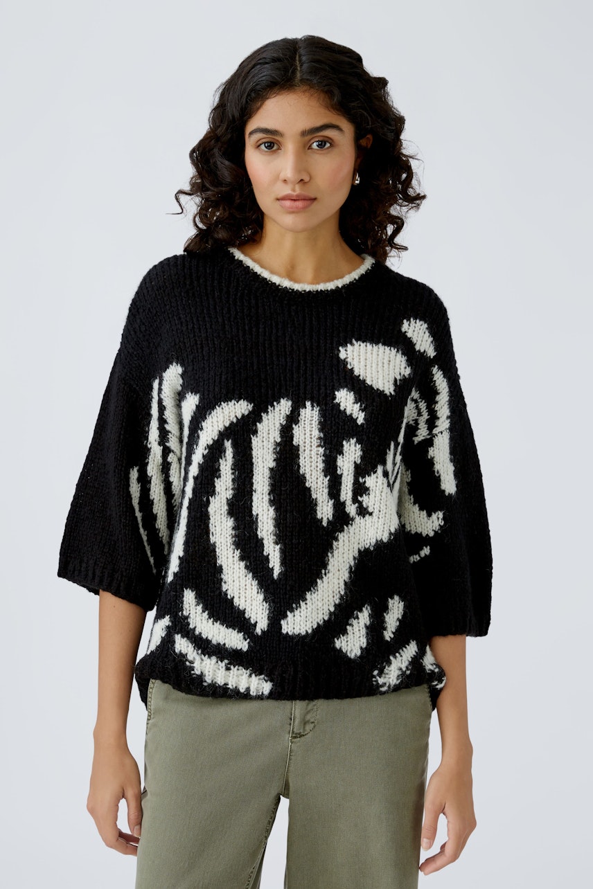 Stylish women's pullover: A woman in a black and white patterned pullover, exuding confidence.