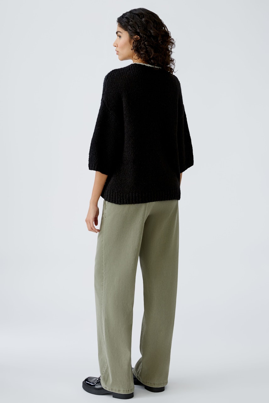 Stylish women's pullover: A woman in a black oversized pullover paired with relaxed-fit trousers.