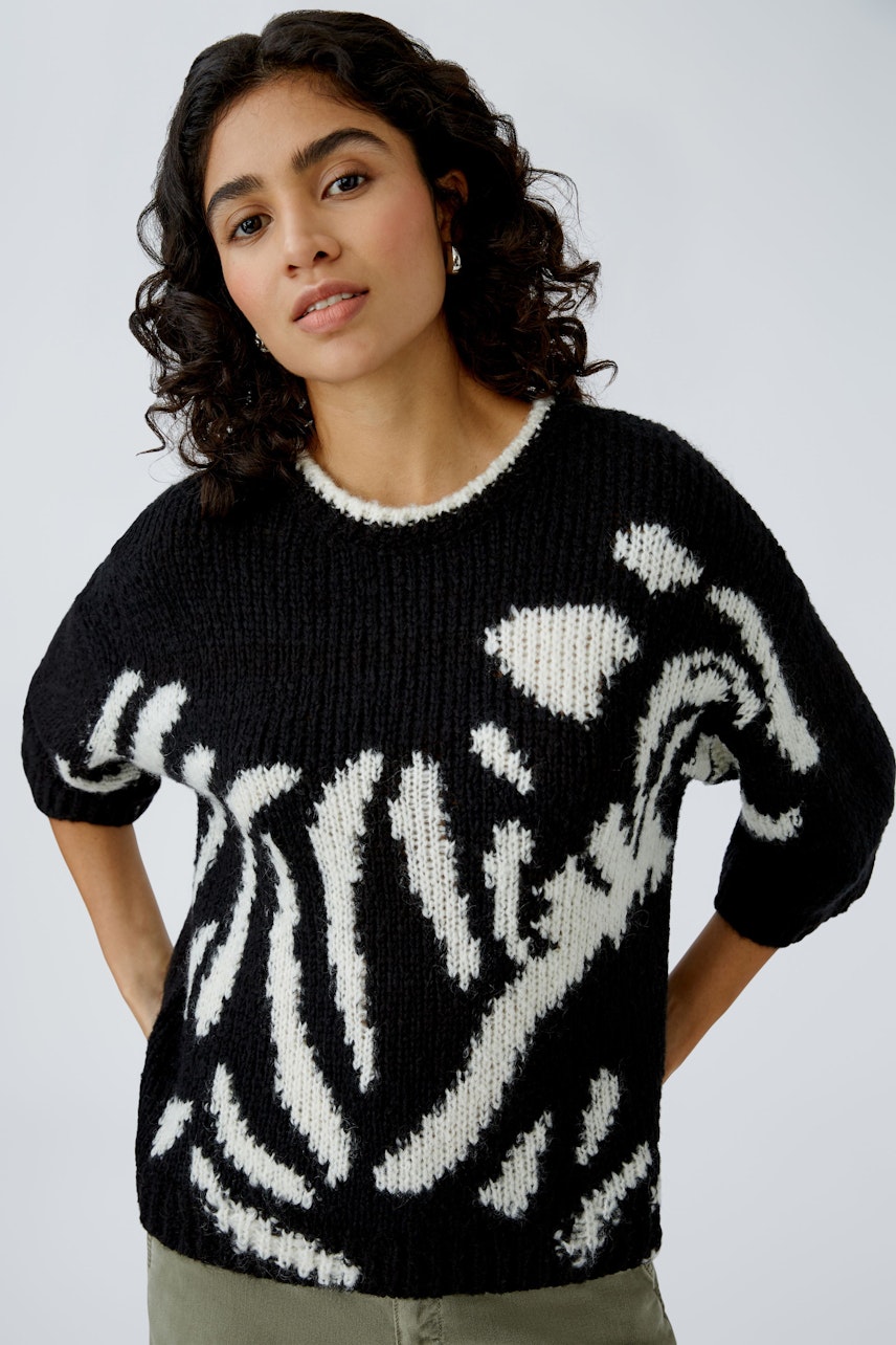 Stylish women's pullover: A woman in a black and white patterned knit pullover, exuding confidence.