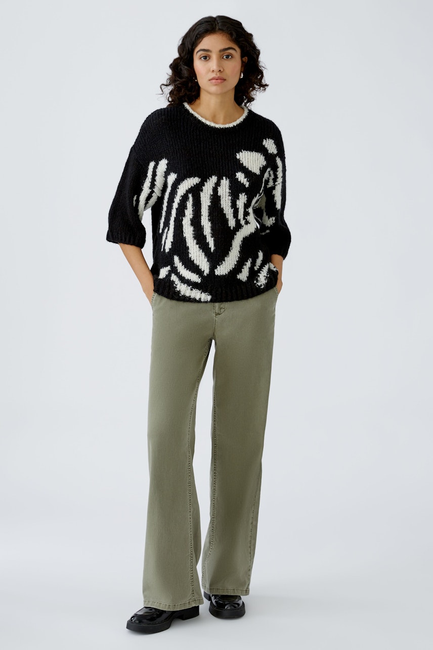 Stylish women's pullover: A woman in a black and white striped pullover paired with relaxed-fit pants.