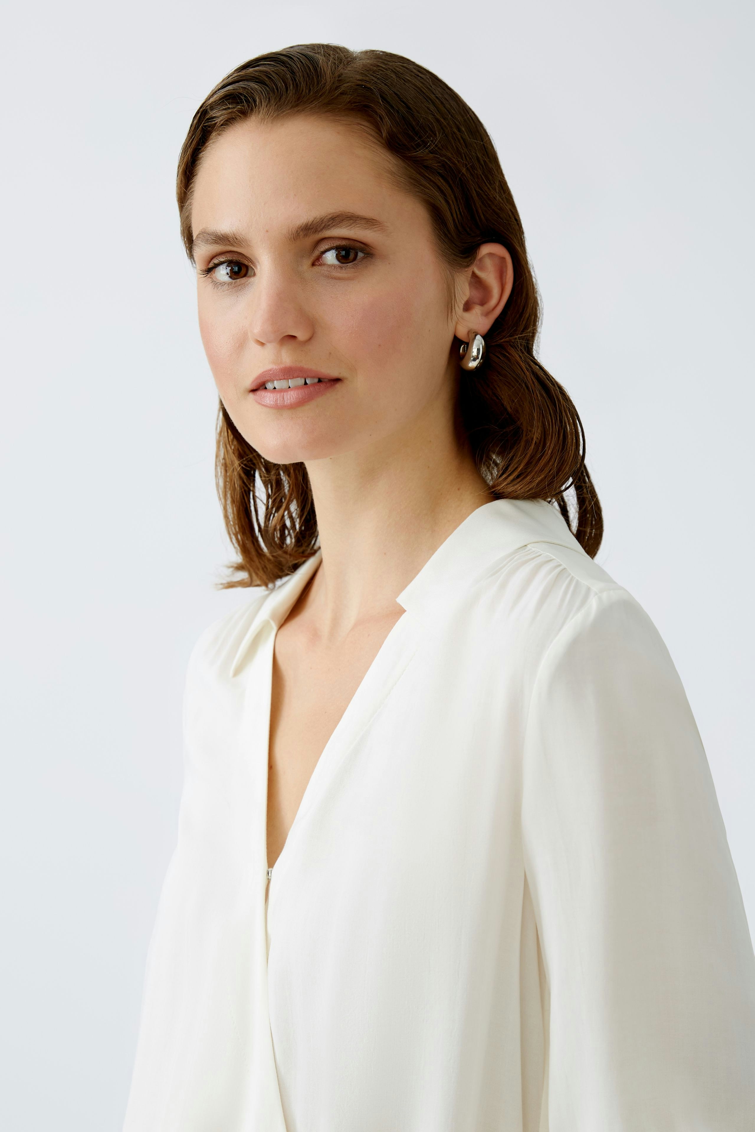 Elegant women's blouse: A woman in a white blouse with a soft collar, exuding sophistication.