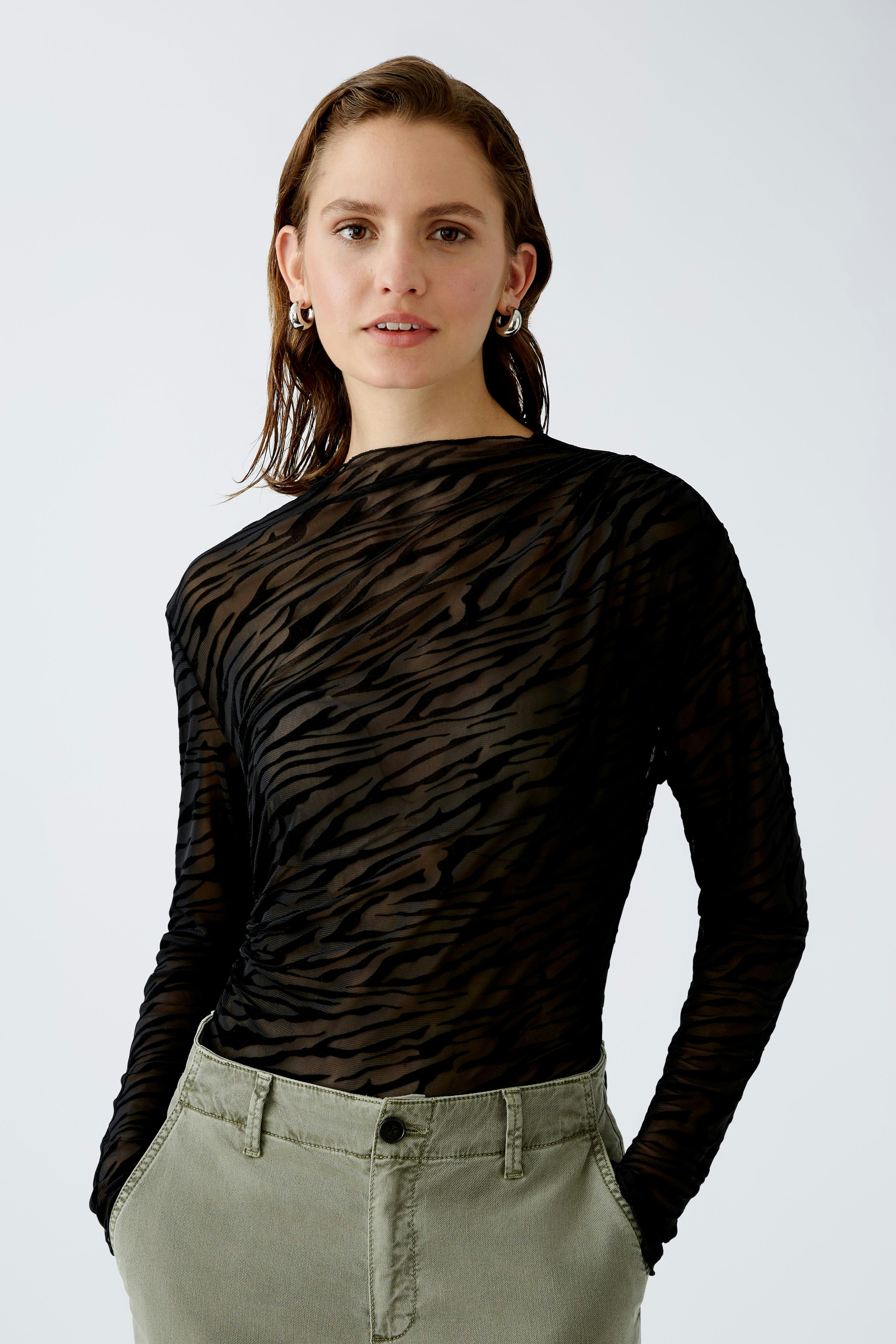 Stylish long-sleeve shirt: Confident woman in a fitted black top with subtle stripes.
