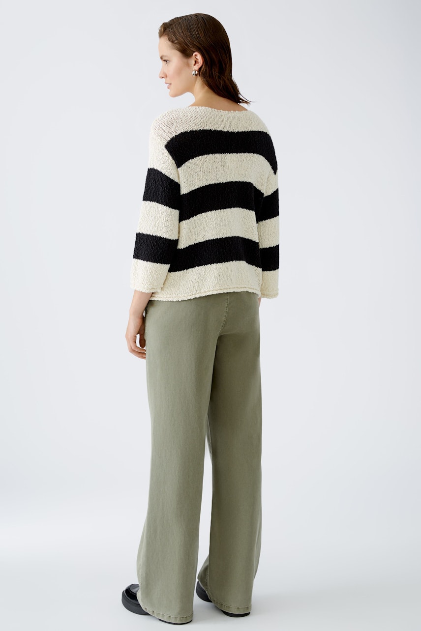 Stylish women's pullover: A woman in a striped pullover with a relaxed fit, paired with wide-leg pants.