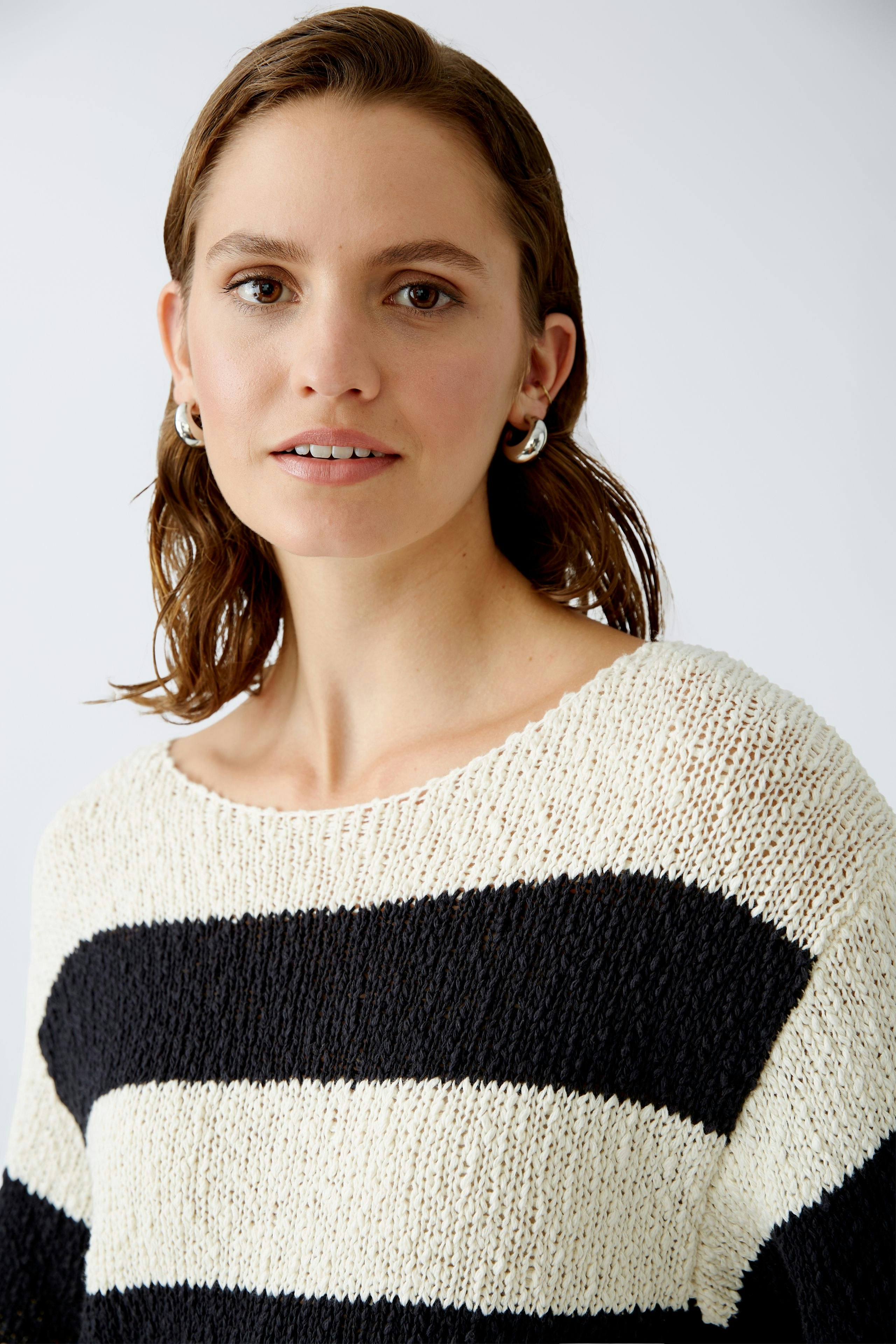 Modern women's pullover: A woman in a striped pullover with a relaxed fit and soft texture.