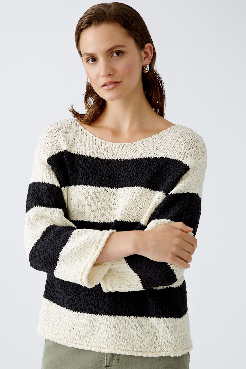 Stylish women's pullover: A woman in a cream and black striped pullover, exuding casual elegance.