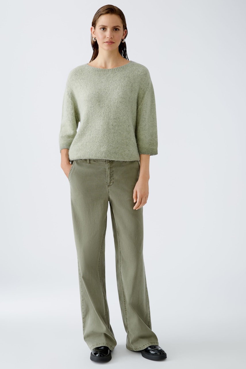 Stylish women's pullover: A woman in a light green pullover paired with relaxed-fit pants.