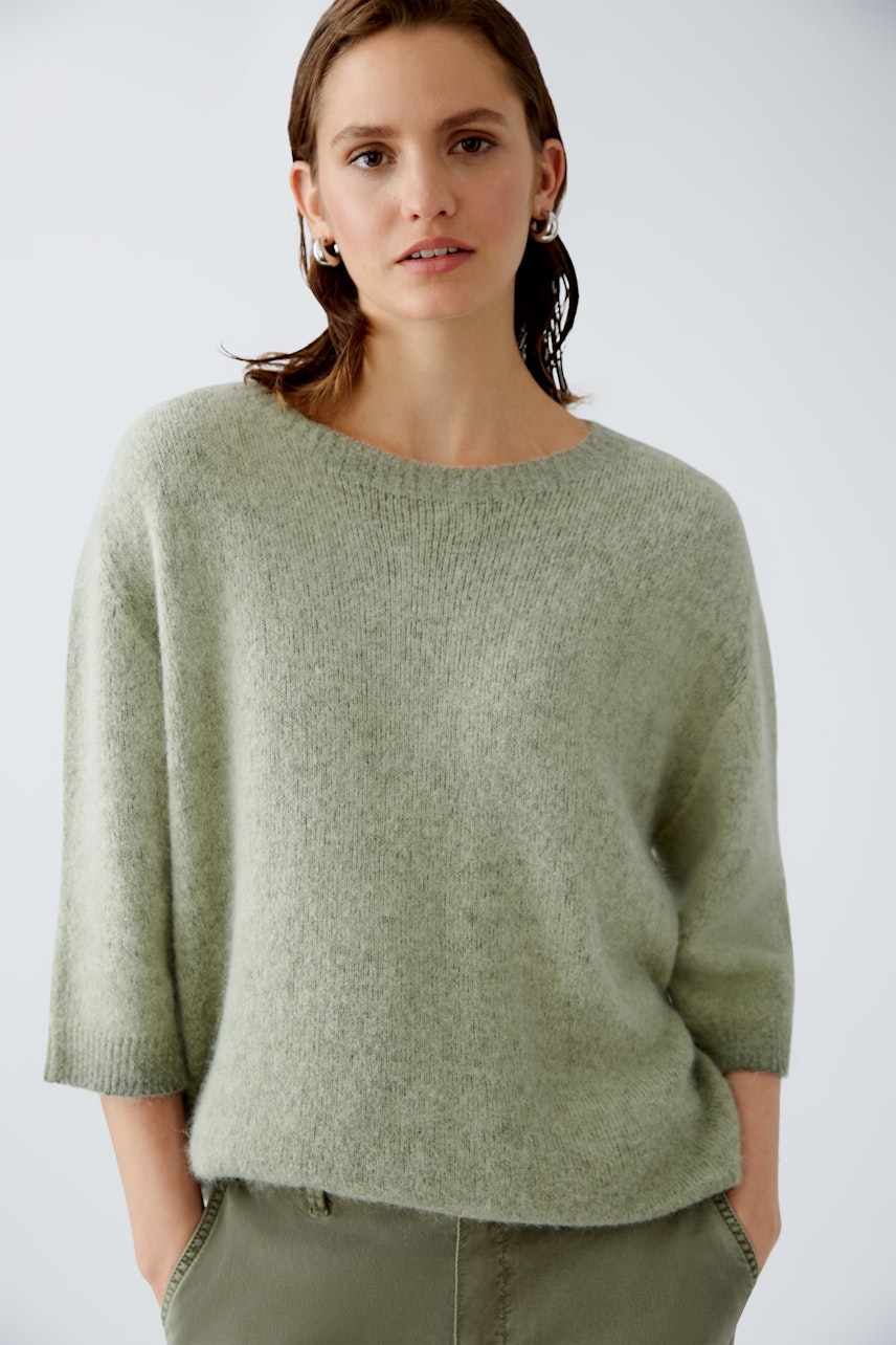 Modern women's pullover: A woman in a soft green pullover with three-quarter sleeves, exuding effortless style.