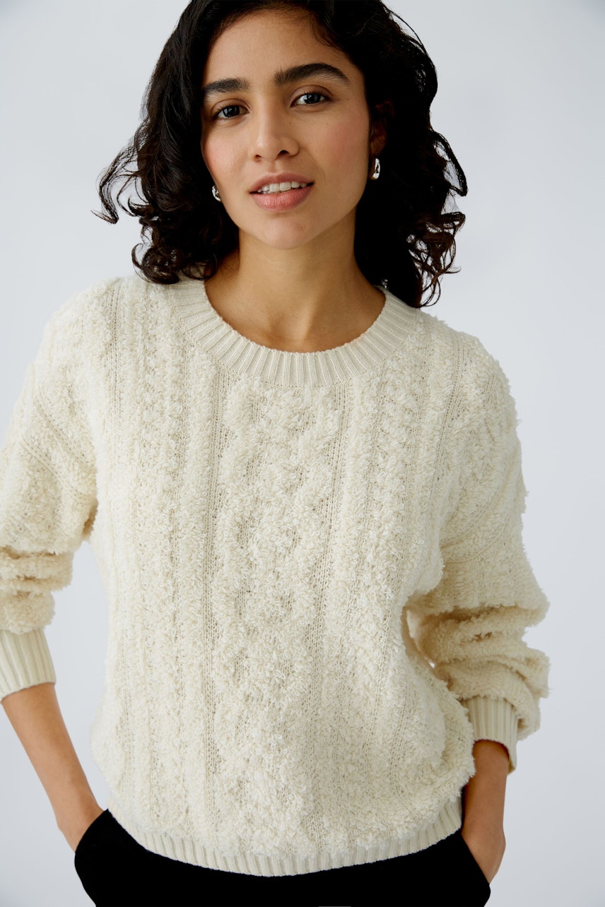 Stylish women's pullover: A woman in a cozy cream pullover with textured knit design.