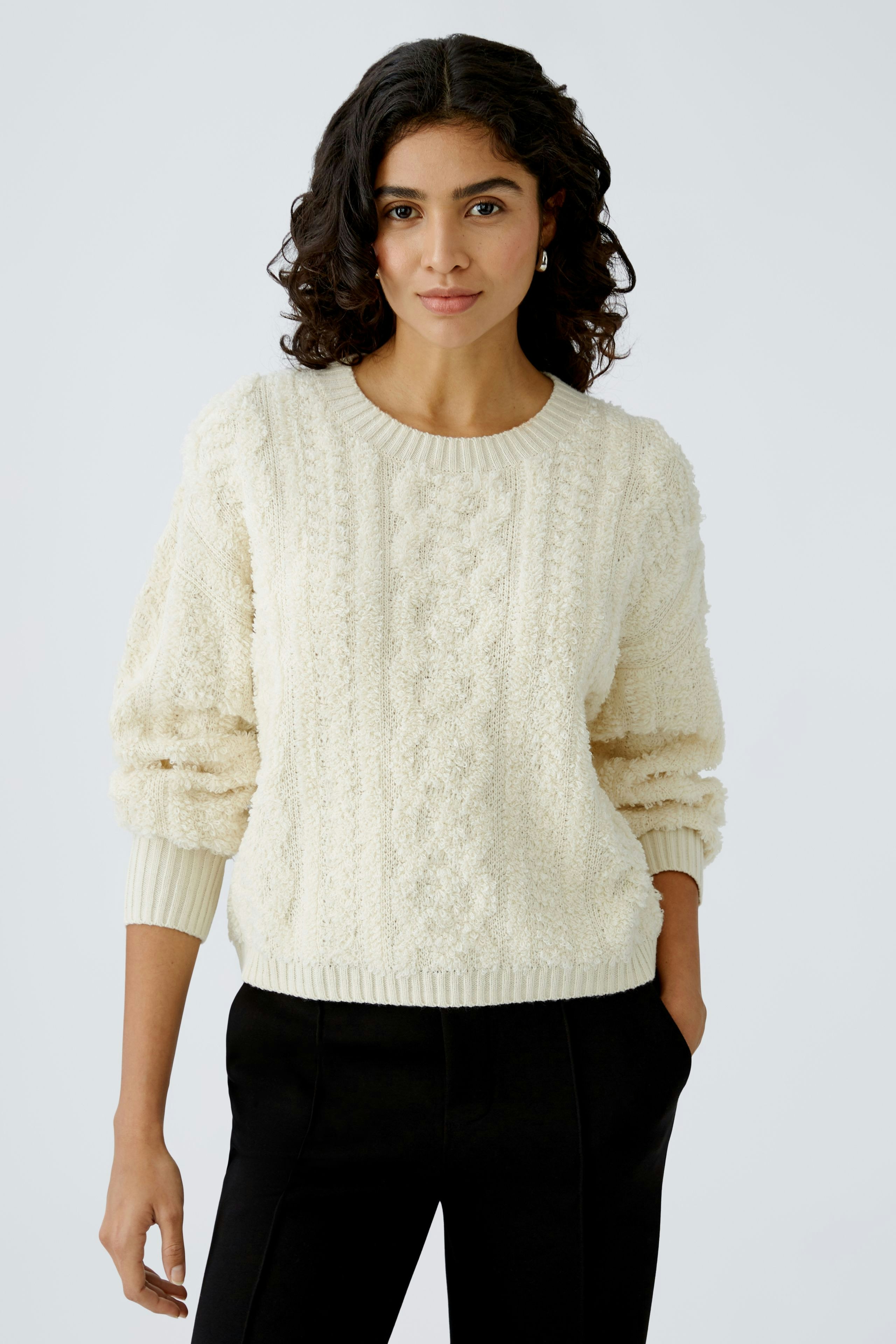 Damen-Pullover: Frau in cremefarbenem, strukturiertem Strickpullover mit lässigem Schnitt.