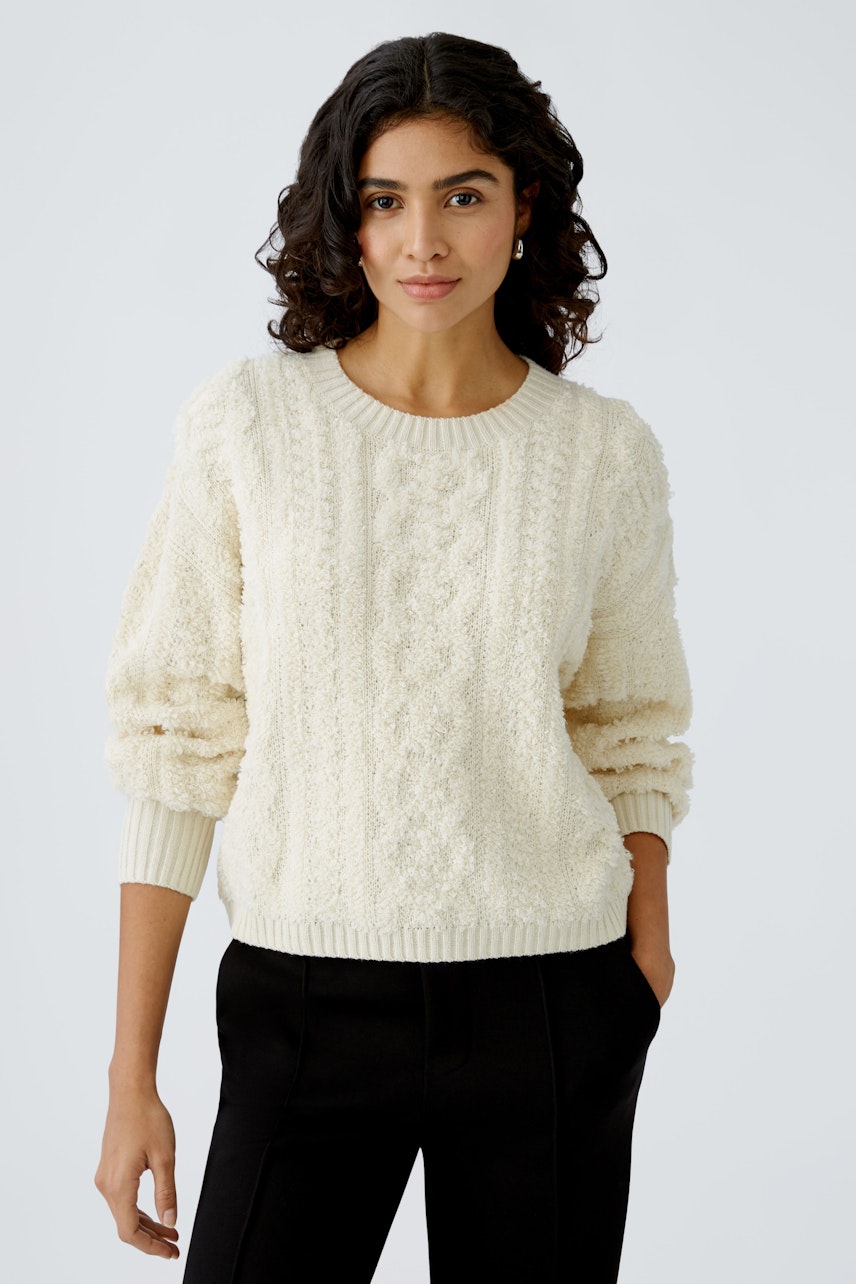 Stylish women's pullover: A woman in a cozy cream pullover with textured details and relaxed fit.