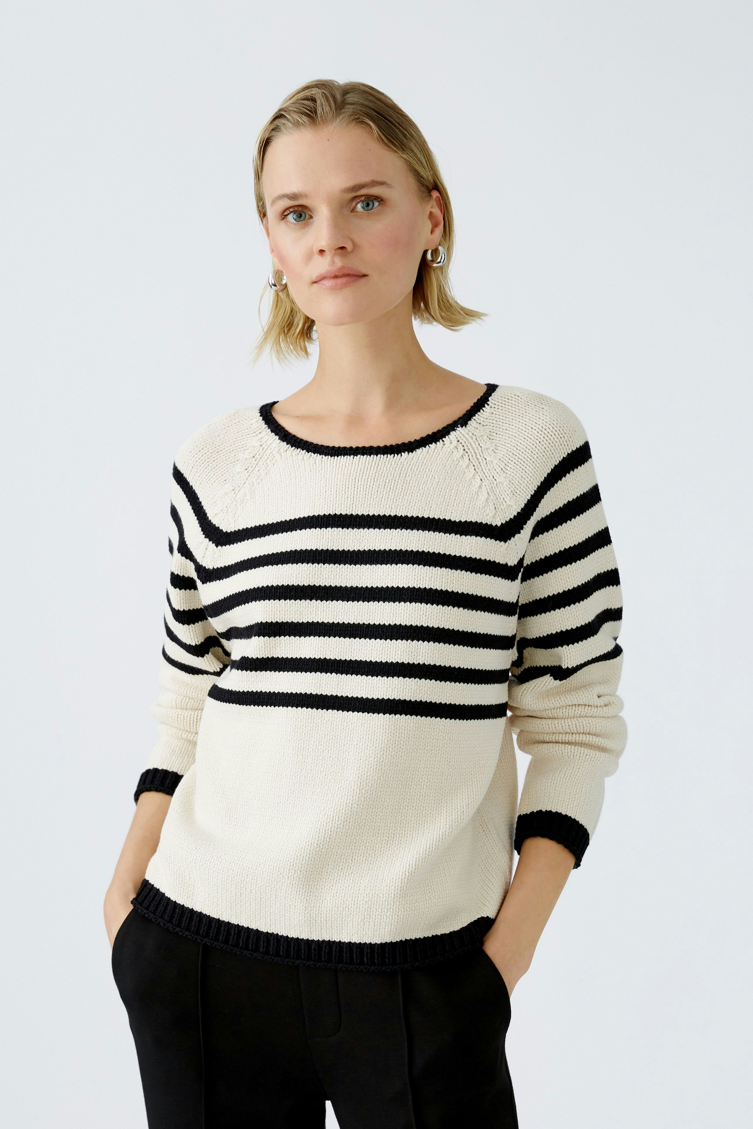 Damen-Pullover: Frau in gestreiftem Pullover in Schwarz und Creme mit lässigem Schnitt.