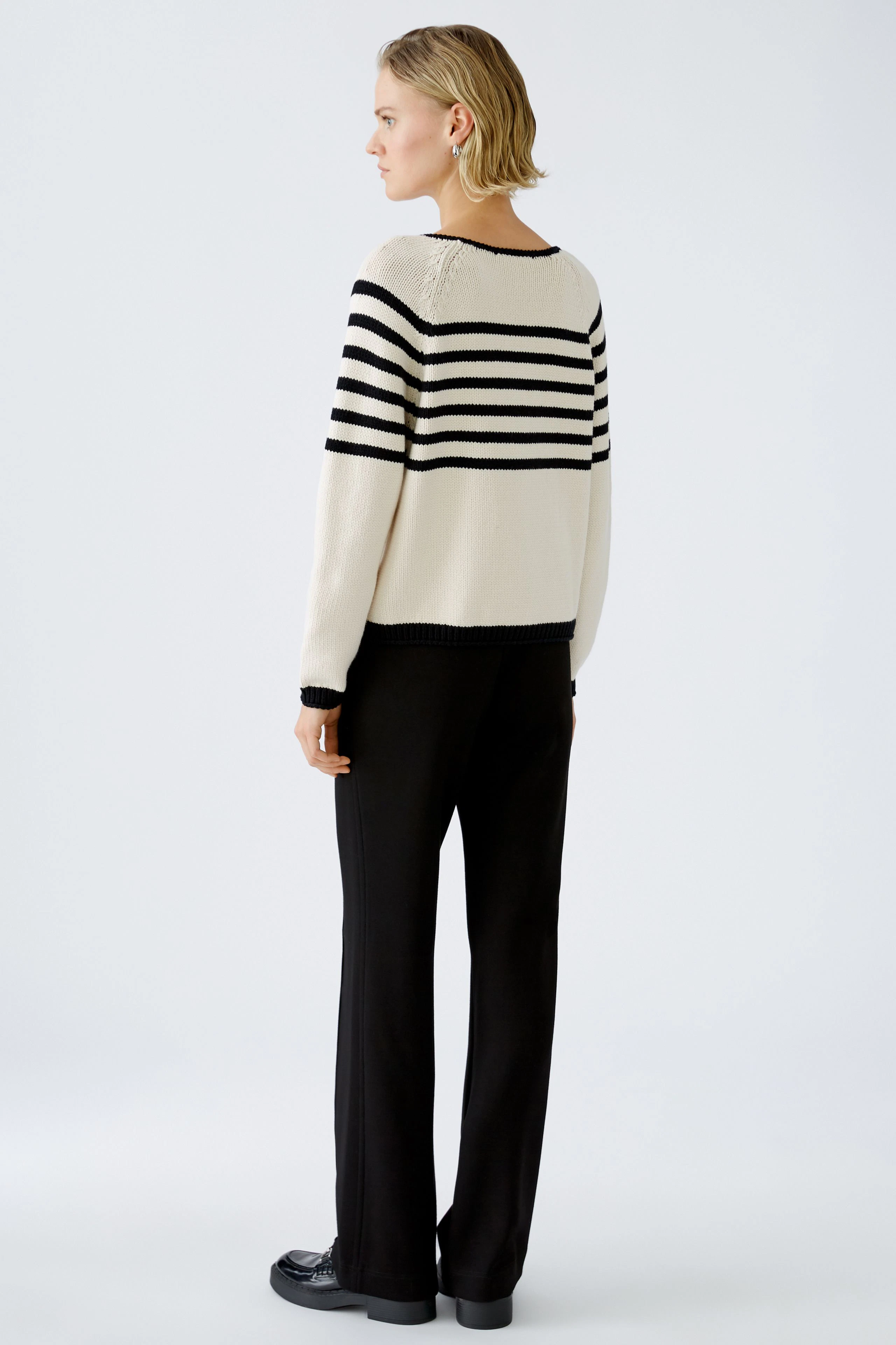 Stylish women's pullover: A woman in a striped pullover with a relaxed fit, paired with black trousers.