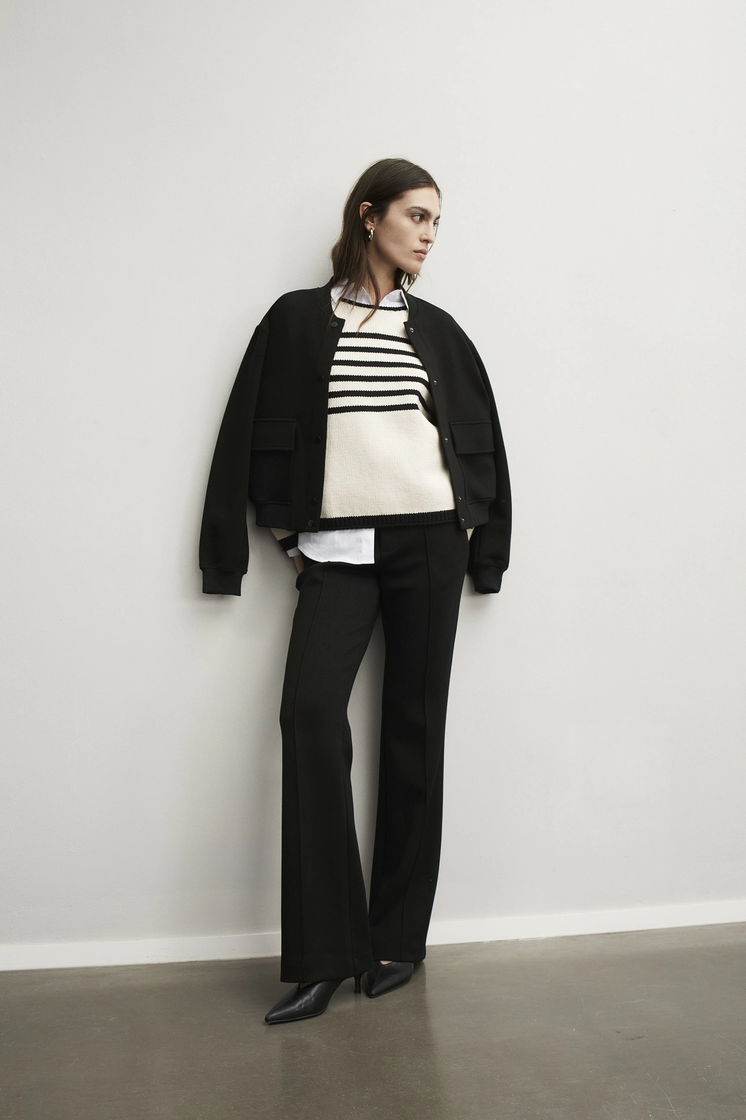 Stylish women's pullover: A woman in a striped pullover layered under a bomber jacket.