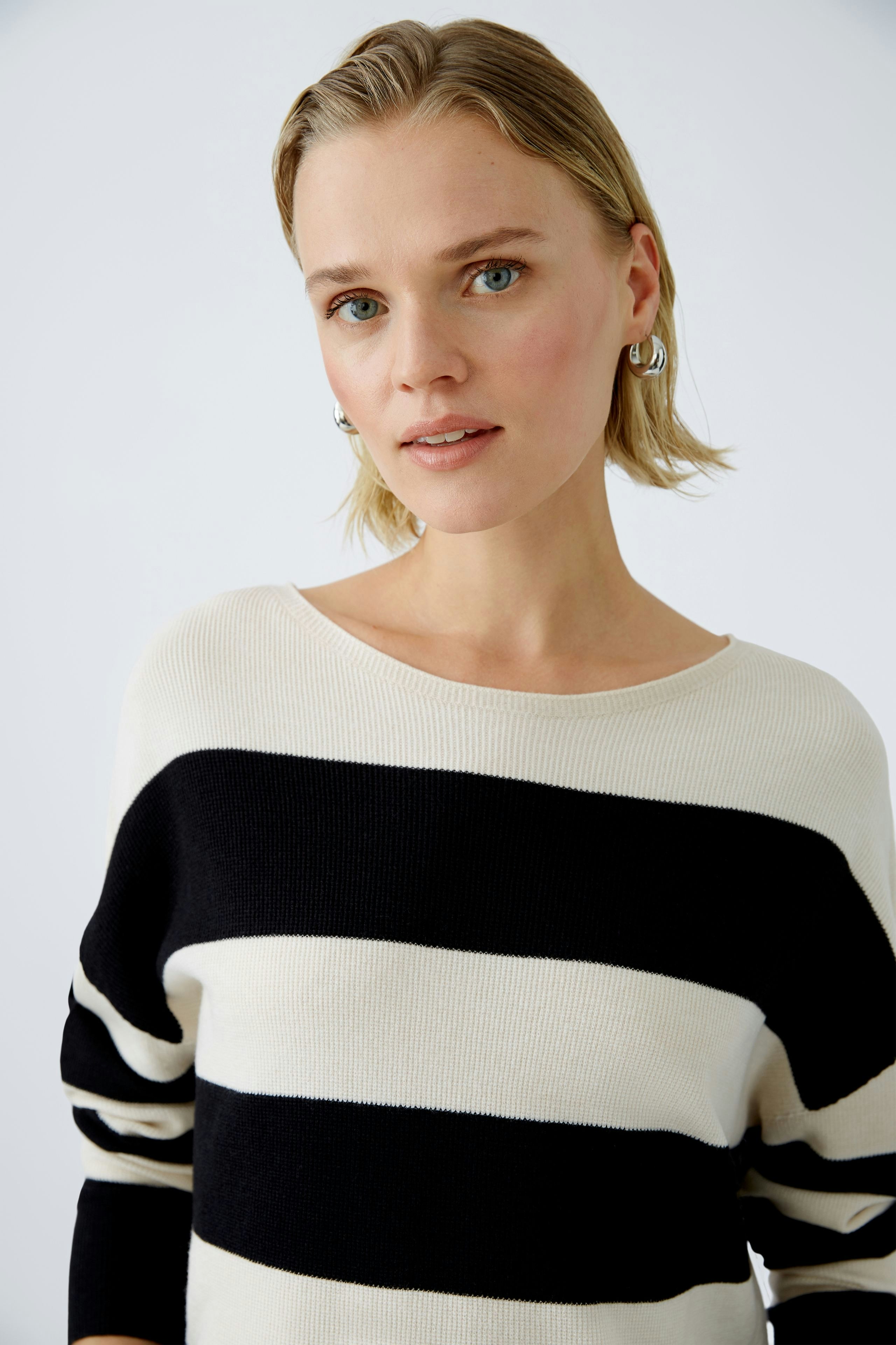 Damen-Pullover: Frau in gestreiftem Pullover mit Schwarz und Creme, lässig und modern.