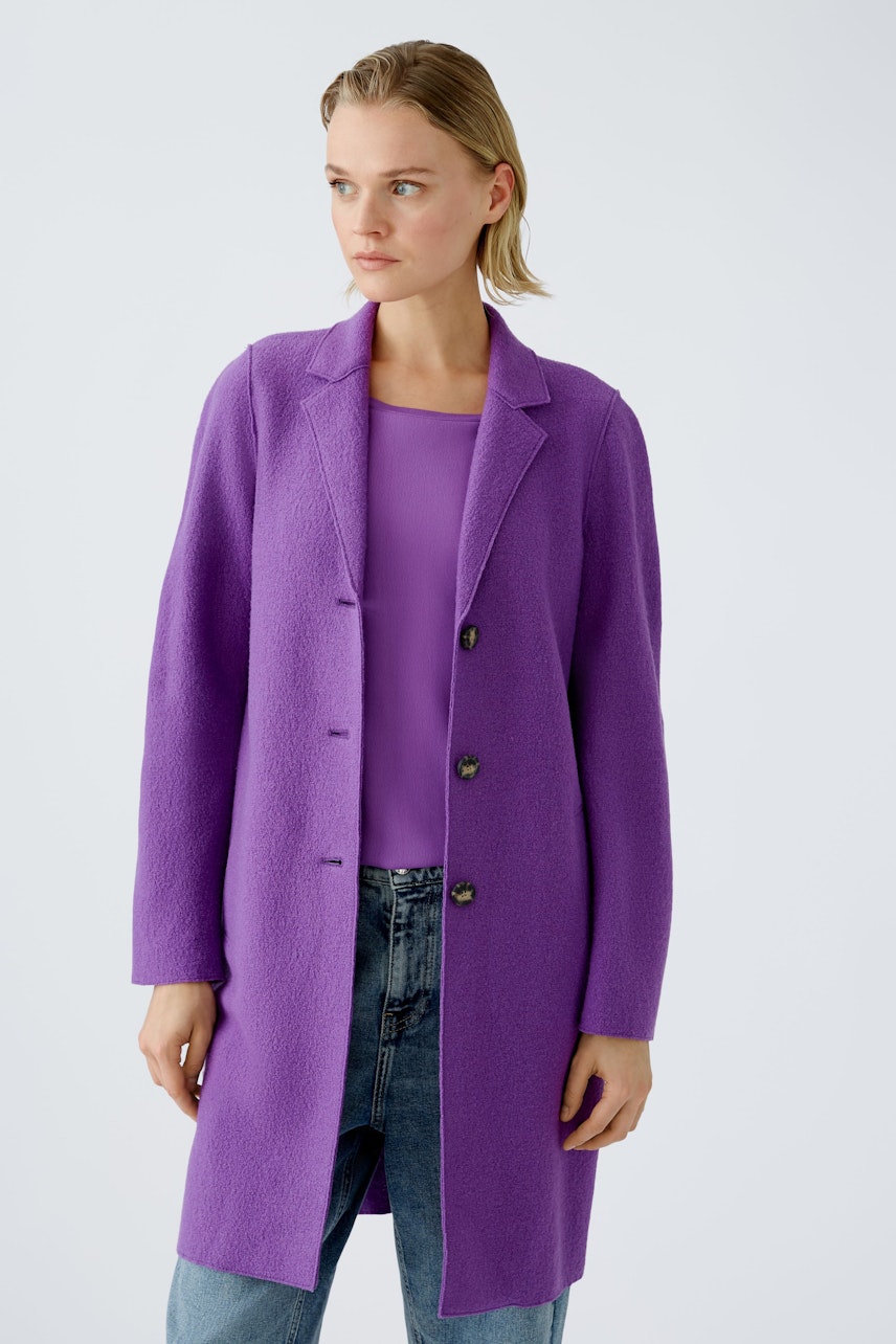 Stylish women's wool coat in vibrant purple, paired with a matching top and casual jeans.