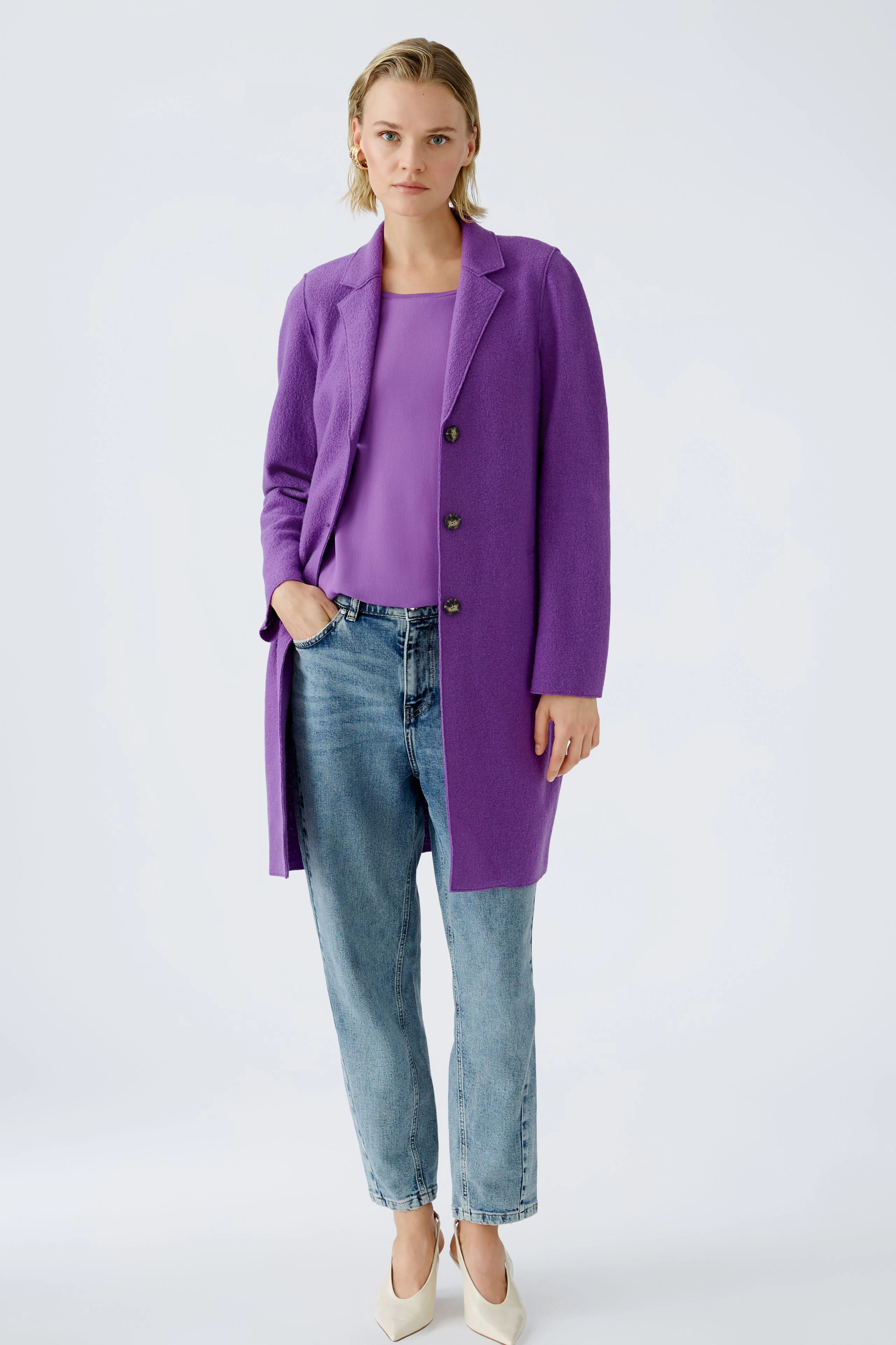 Eleganter Wollmantel: Frau in lila Wollmantel, kombiniert mit lässigem Oberteil und Jeans.