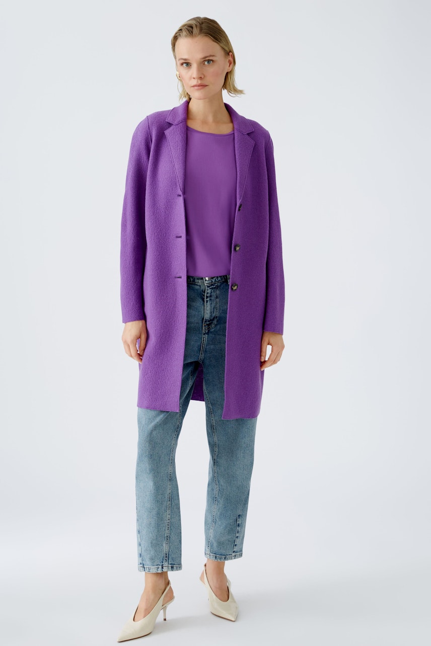 Stylish women's wool coat: A woman in a vibrant purple coat over a top and jeans.