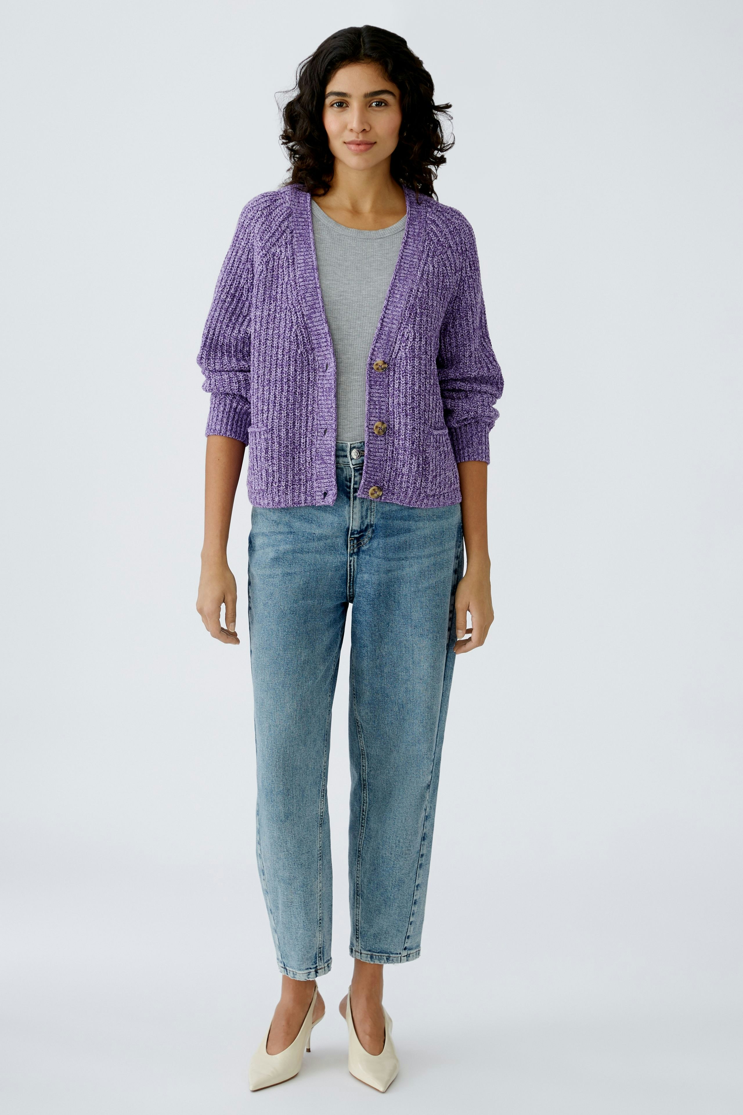 Stylish women's cardigan: A woman in a purple knitted cardigan over a gray top and jeans.