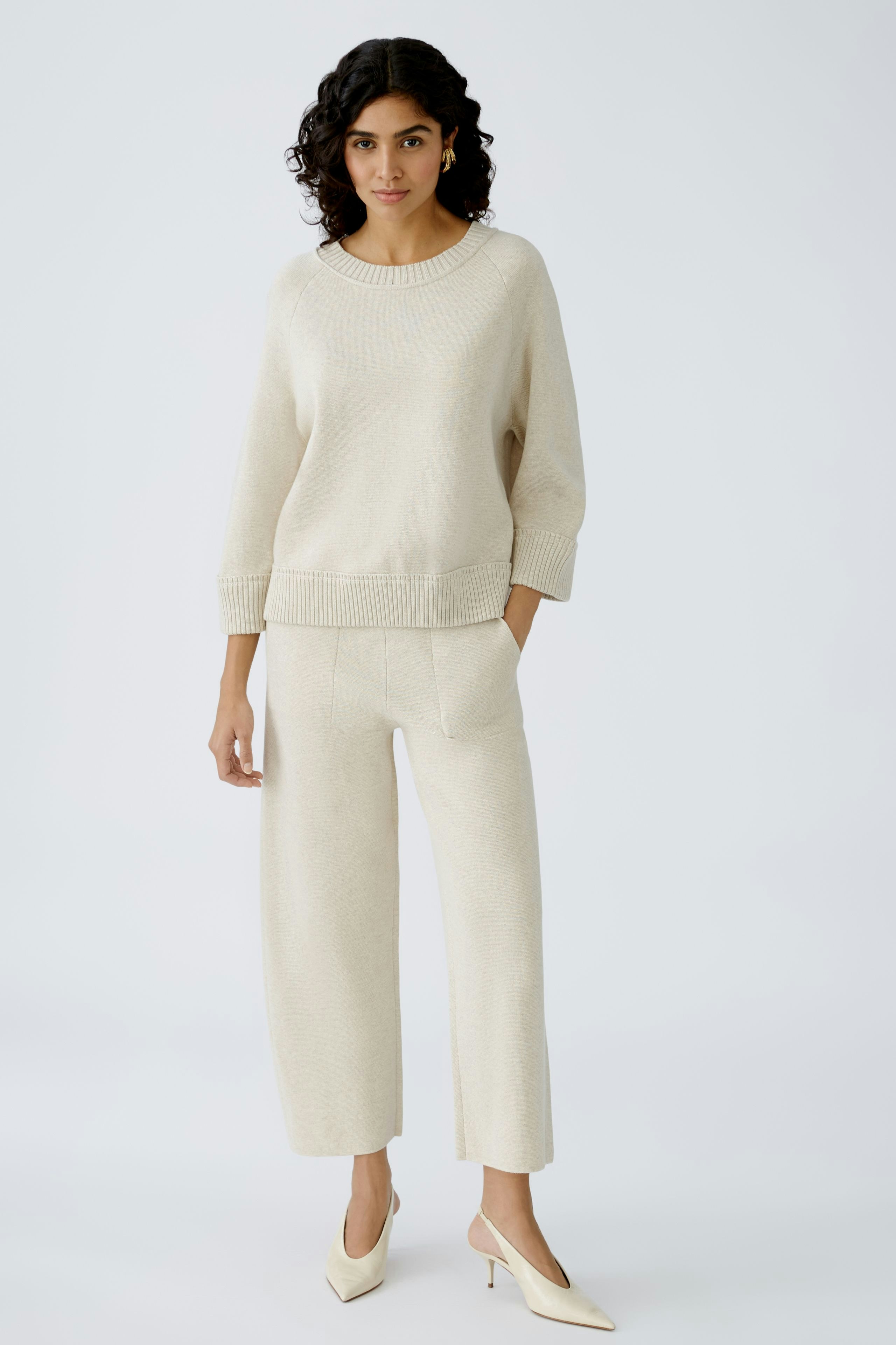 Stylish women's knit pants in soft beige, paired with a matching pullover for a cozy look.