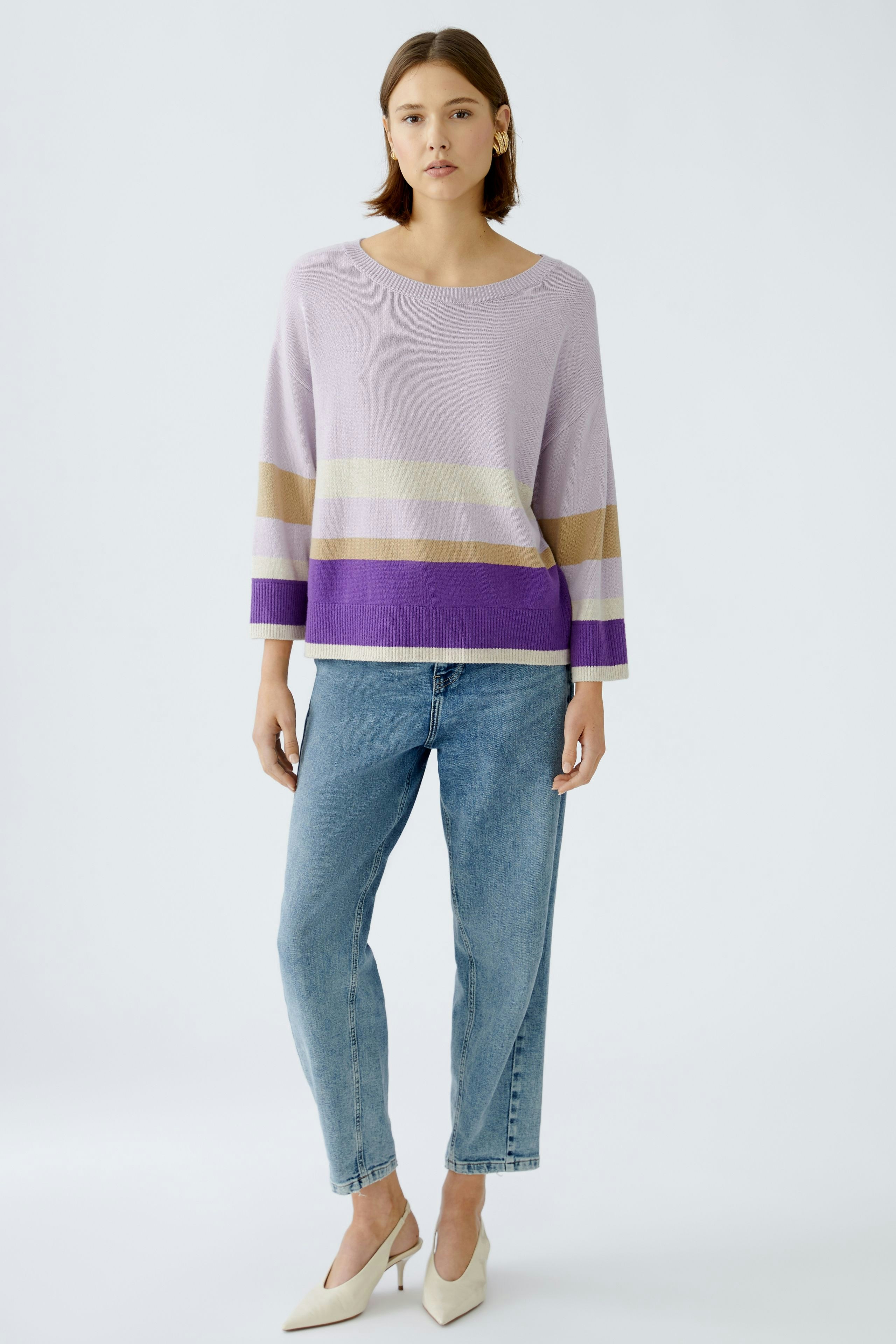 Damen-Pullover: Junge Frau in lila gestreiftem Pullover mit lässigen Jeans und eleganten Schuhen.