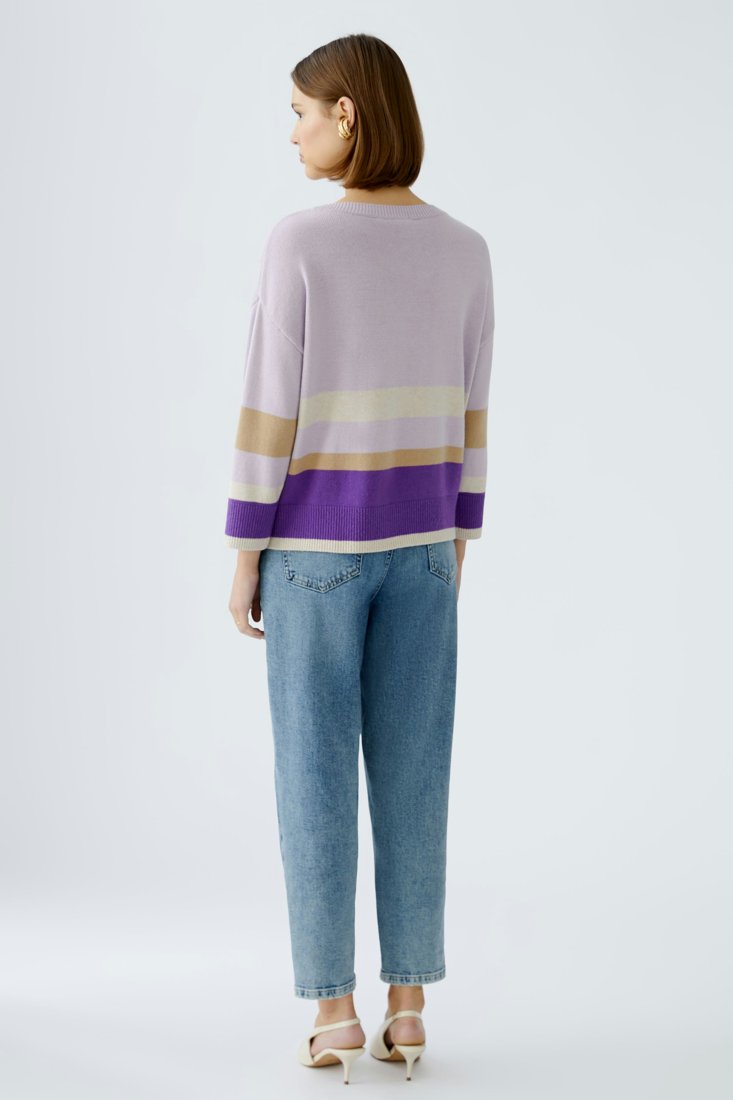 Damen-Pullover in sanften Farben: Frau mit lila, beige und gold gestreiftem Pullover von hinten.