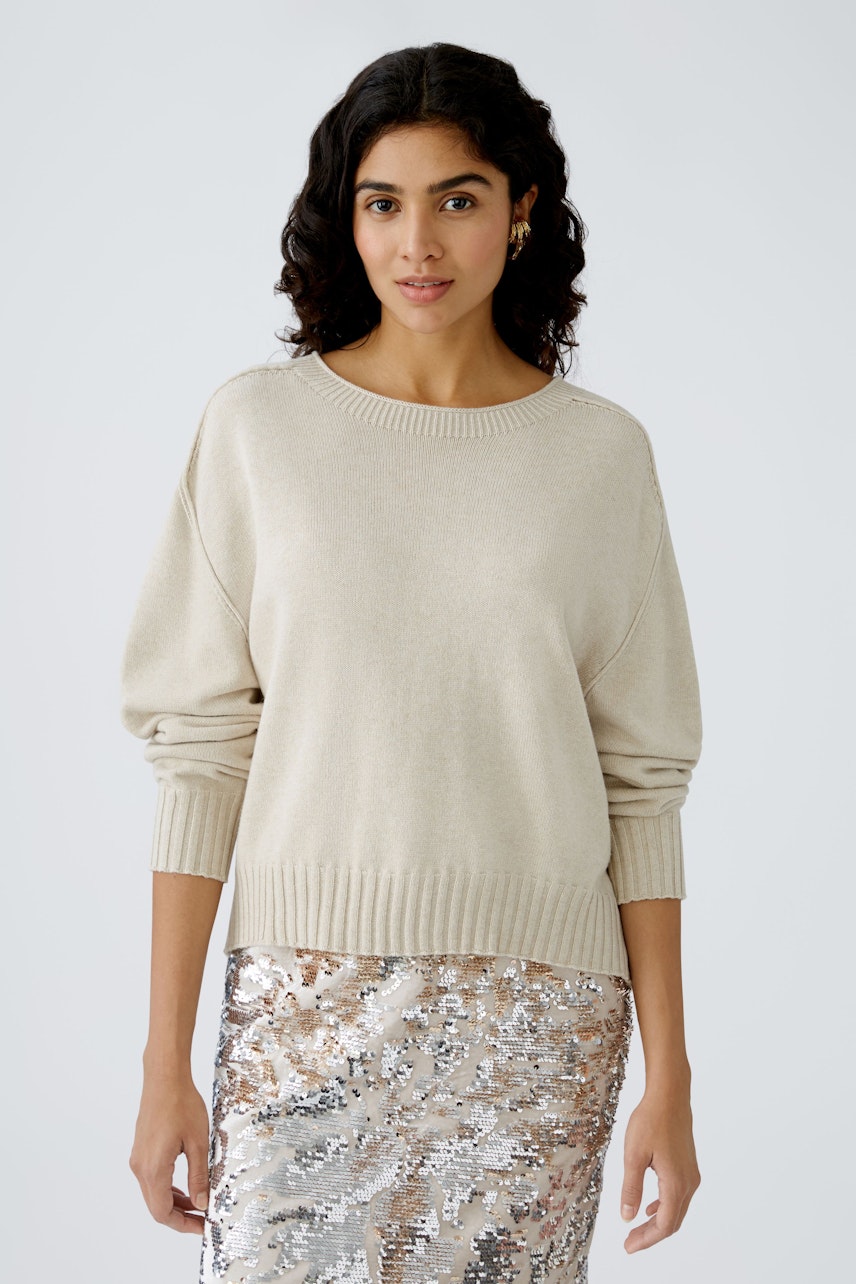 Stylish women's pullover in soft beige, paired with a shimmering silver skirt.