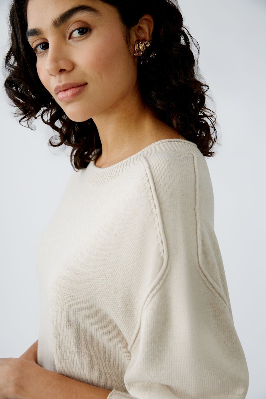 Elegant women's pullover: A woman in a soft beige pullover with a relaxed fit and stylish details.