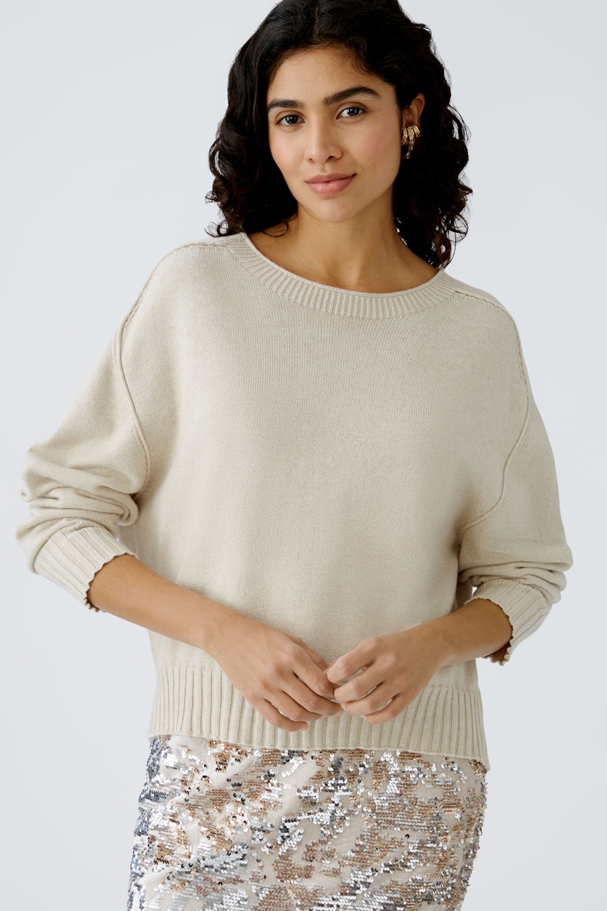 Stylish women's pullover: A woman in a light beige pullover paired with a sparkling skirt.