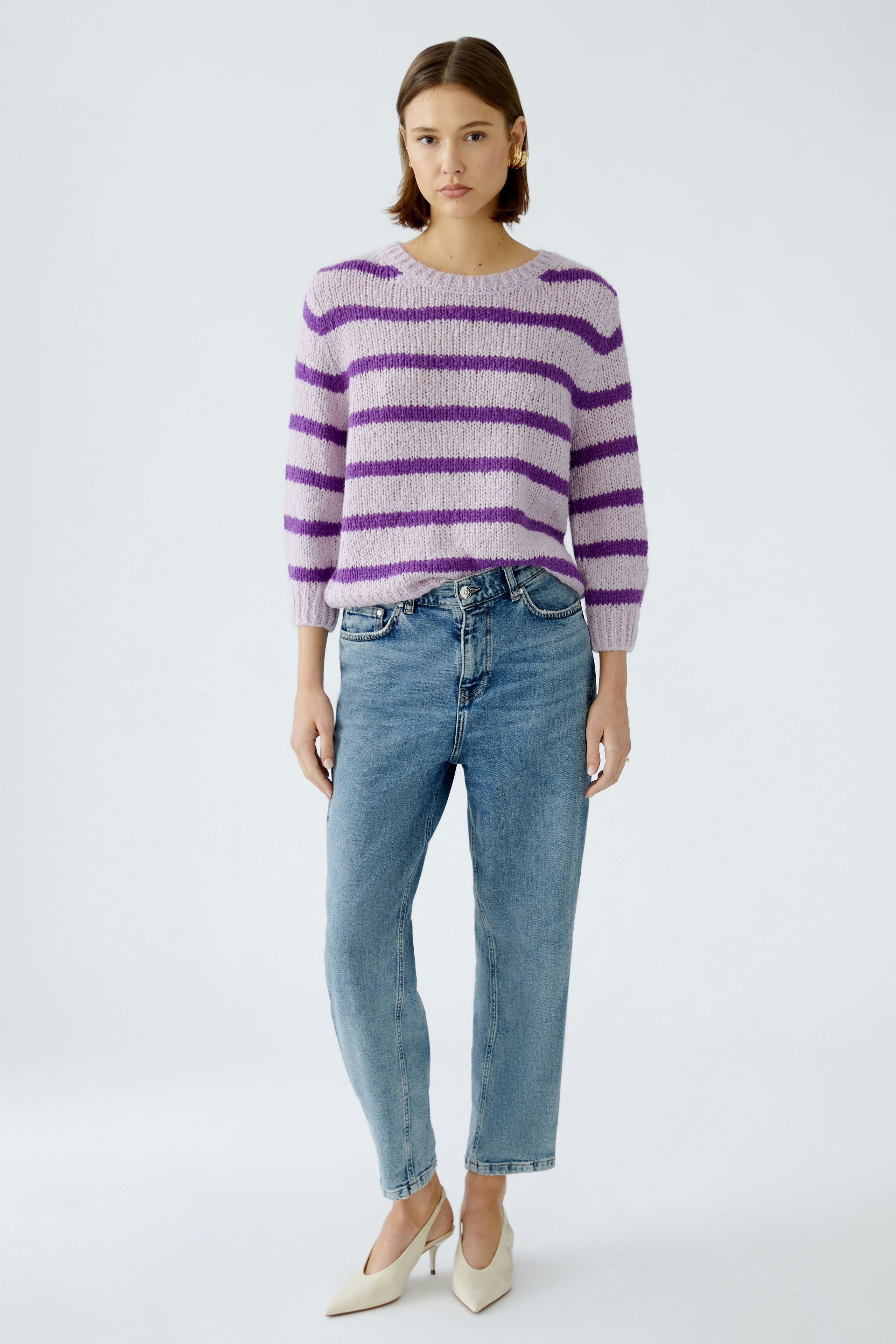 Modern women's pullover: A woman in a striped purple and white pullover paired with jeans.