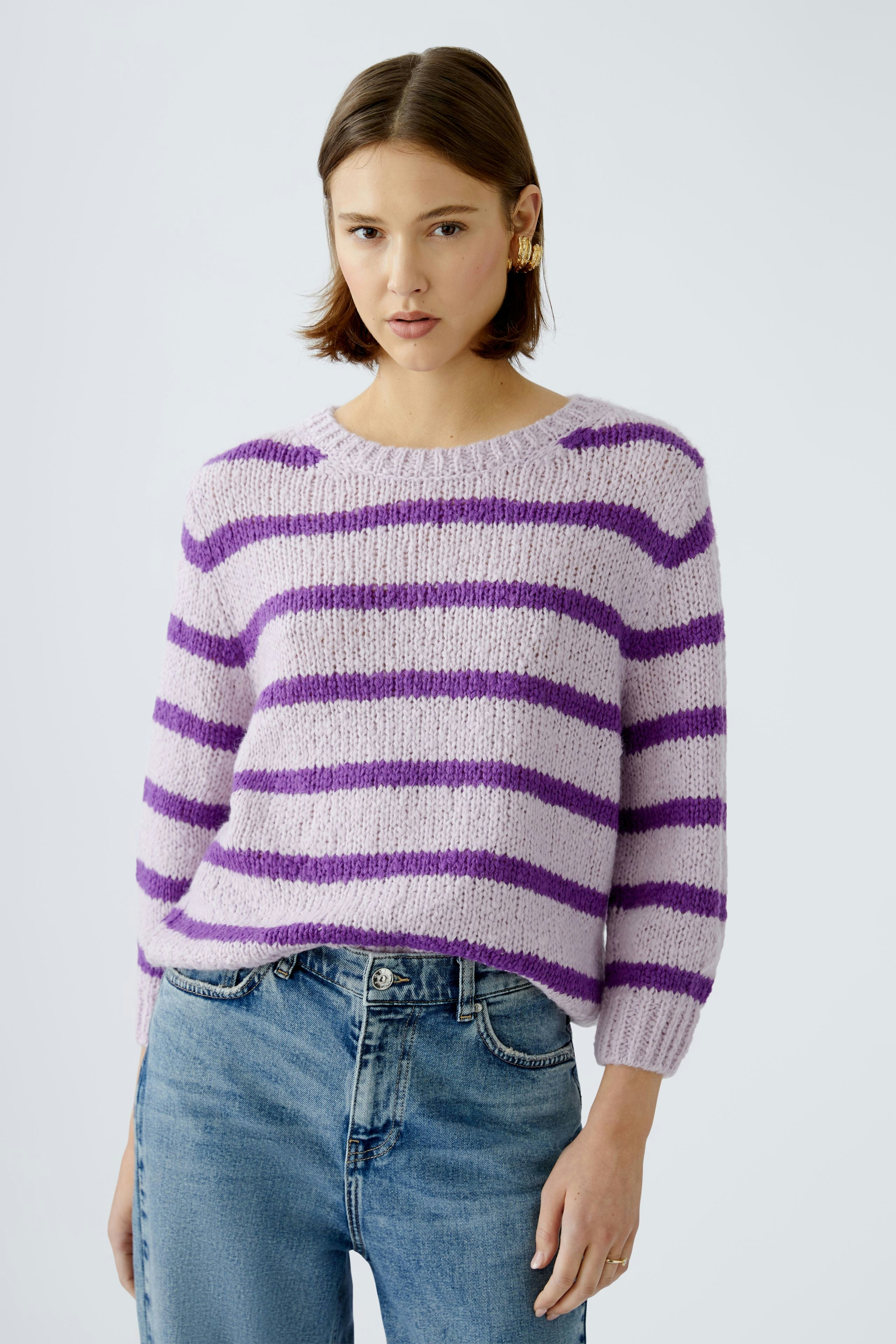 Stylish women's pullover: A woman in a lilac striped pullover paired with jeans, exuding casual elegance.