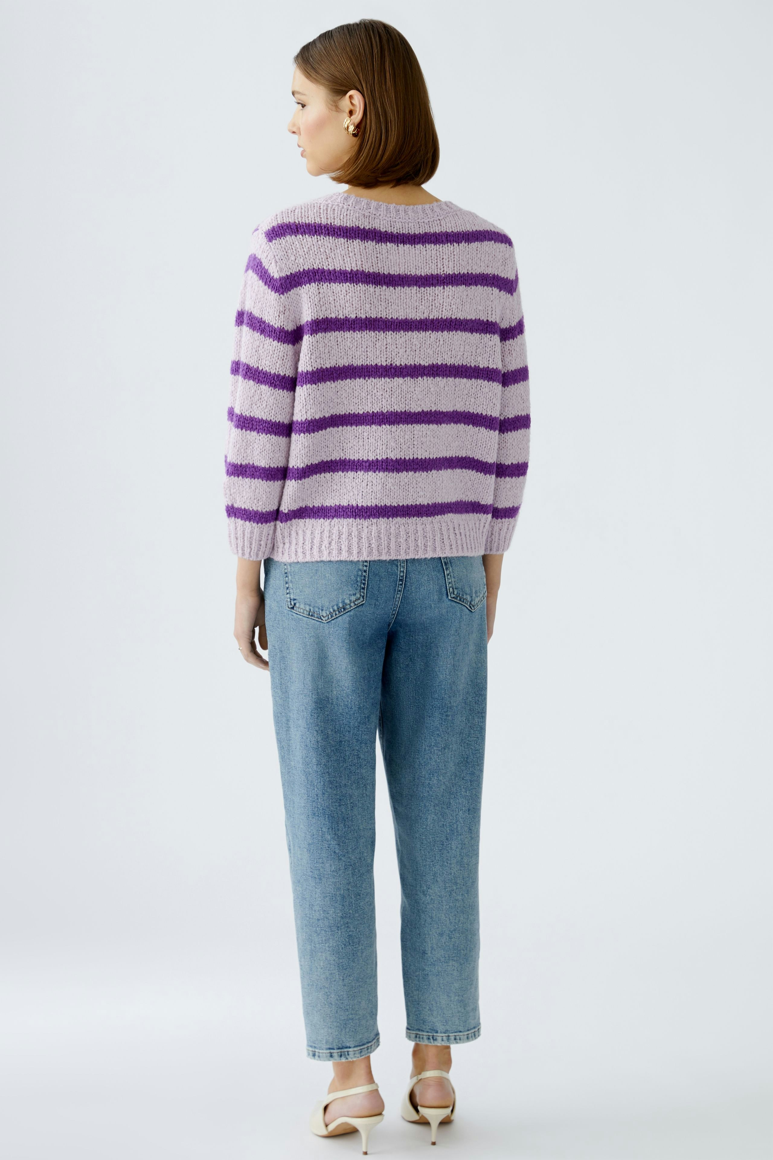 Stylish women's pullover: A woman in a cozy striped pullover with a relaxed fit, paired with jeans.