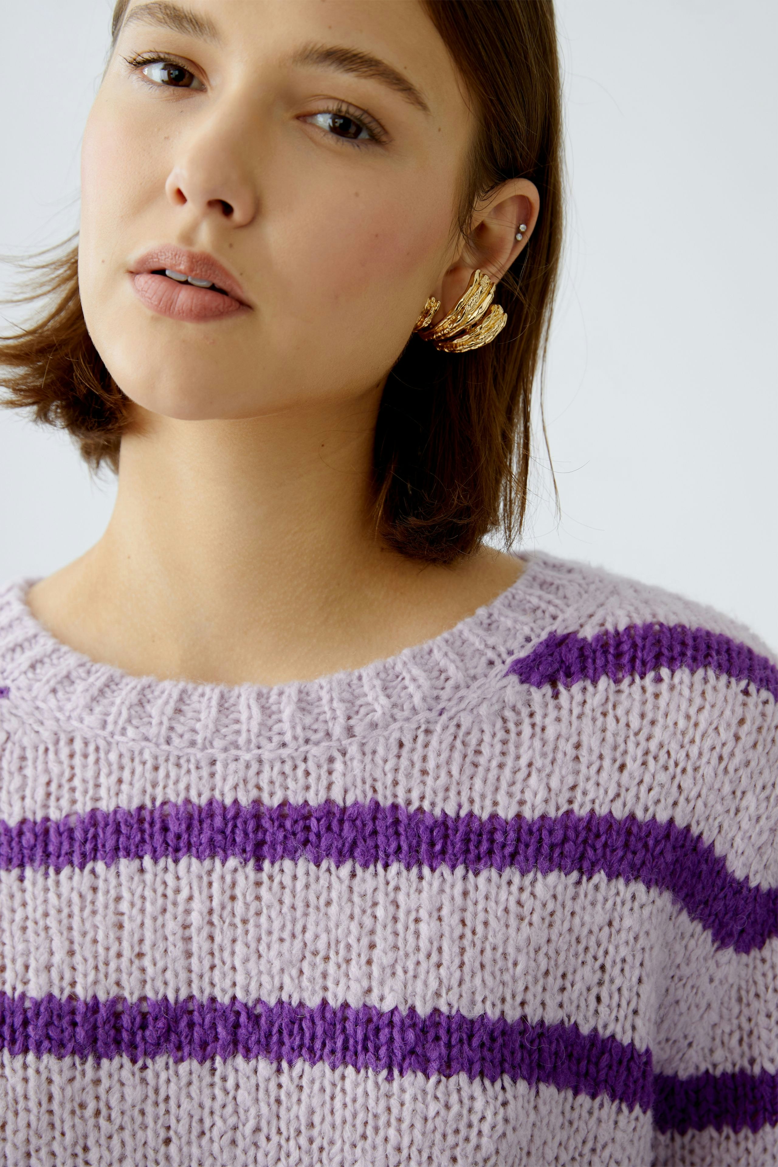 Stylish women's pullover: A woman in a lilac striped pullover with a relaxed fit.
