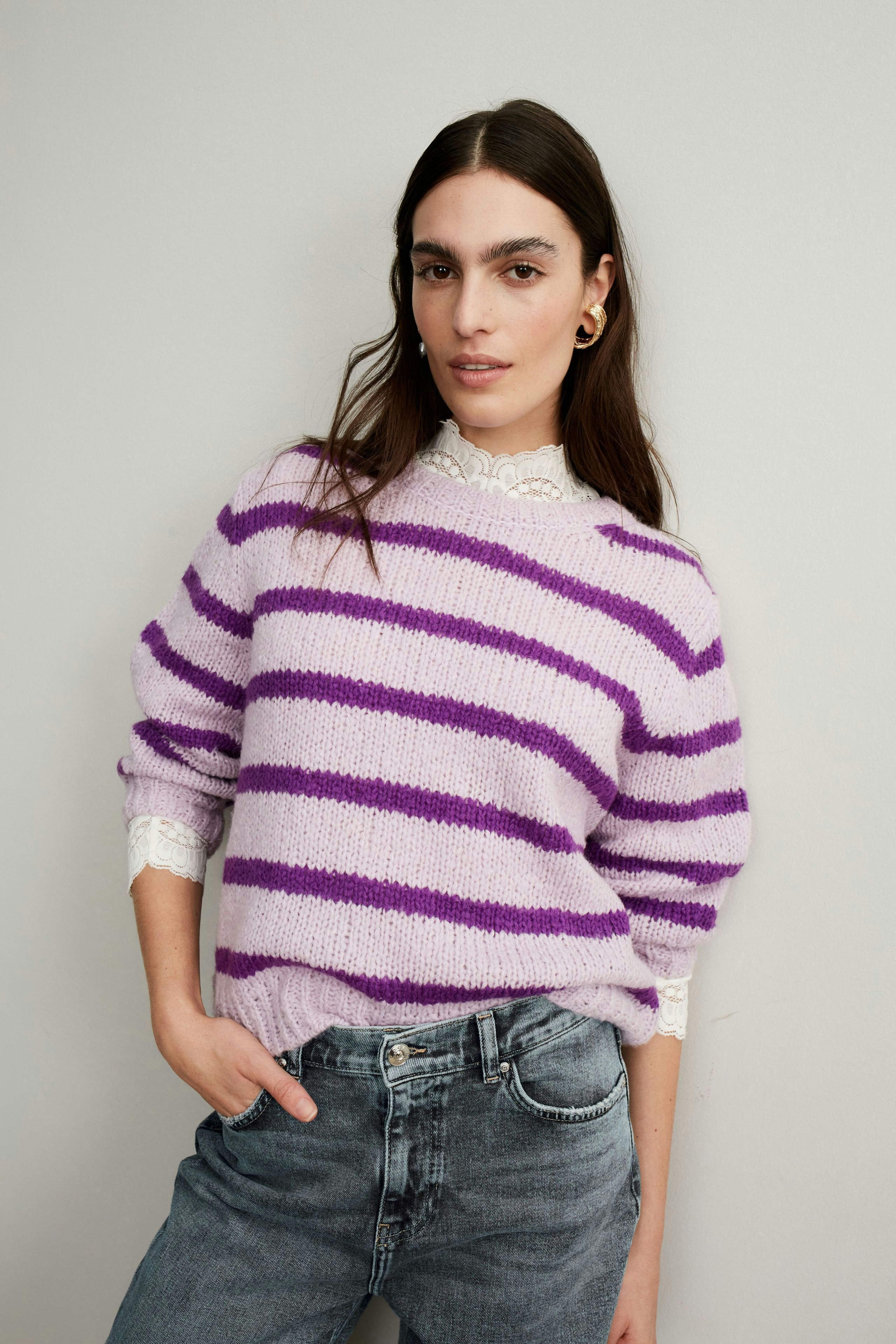 Stylish women's pullover: A woman in a lilac striped pullover with lace details, paired with jeans.