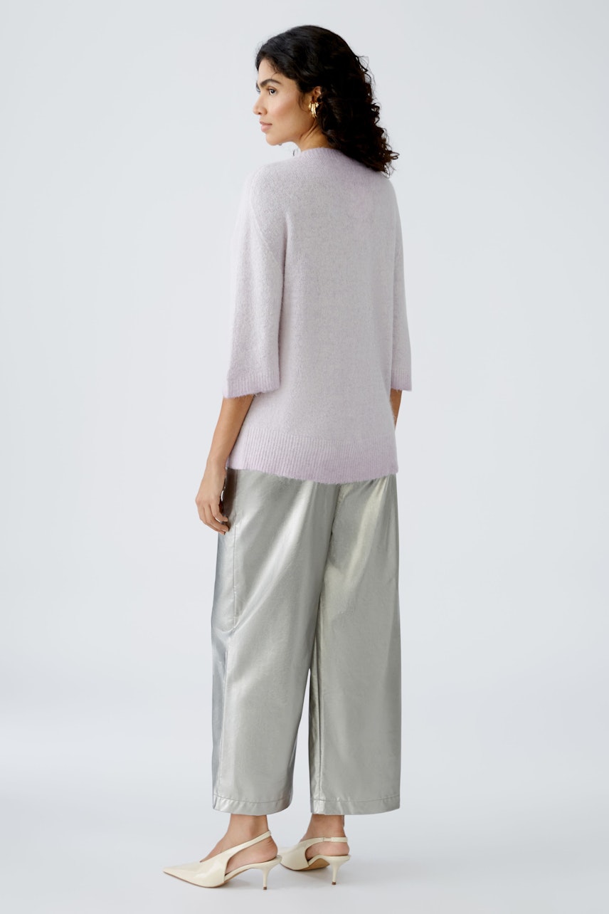 Stylish women's pullover in soft lilac, paired with shiny silver trousers, showcasing a modern look.