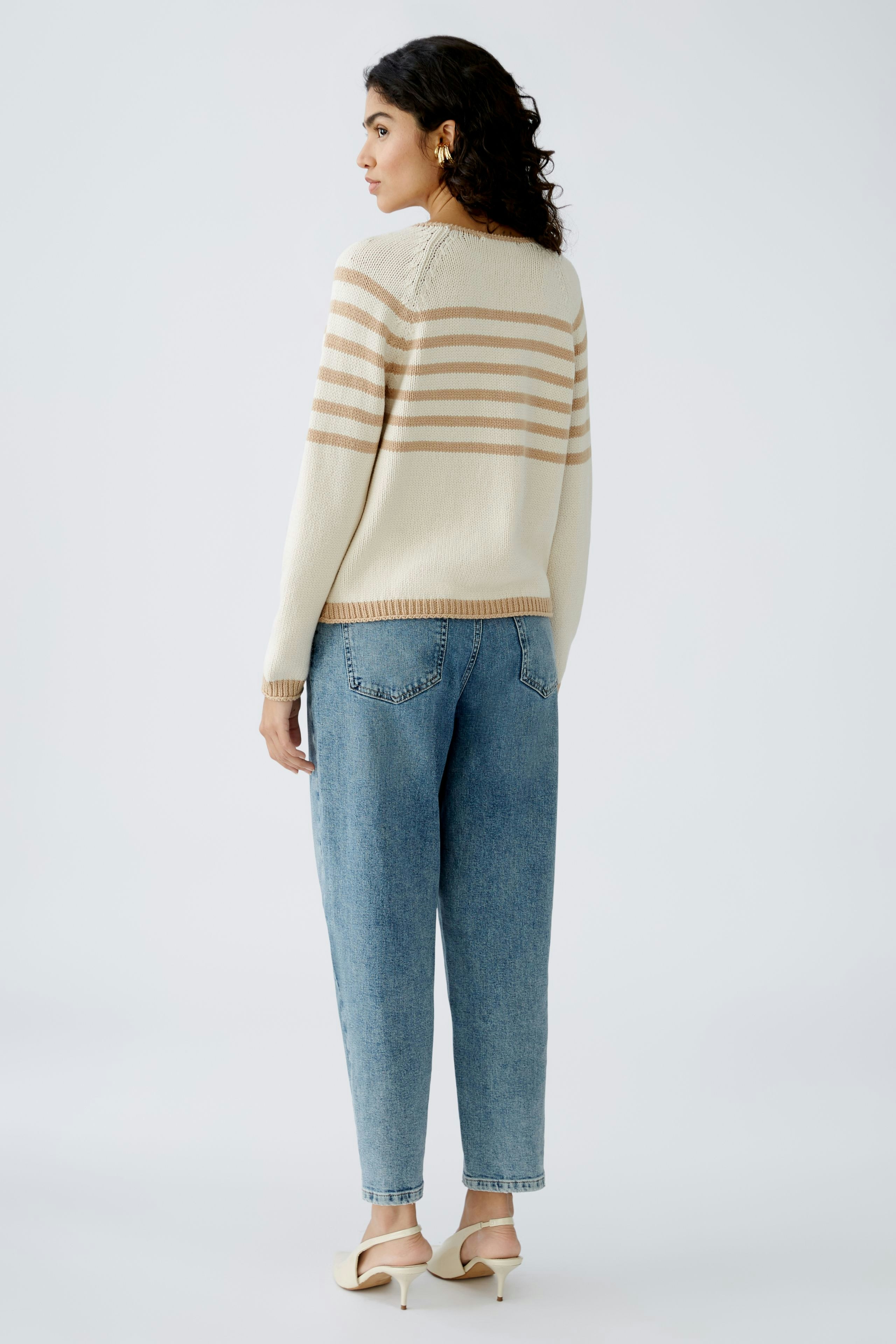 Damen-Pullover: Frau in beigem Pullover mit Streifen und lässigen Jeans von hinten.