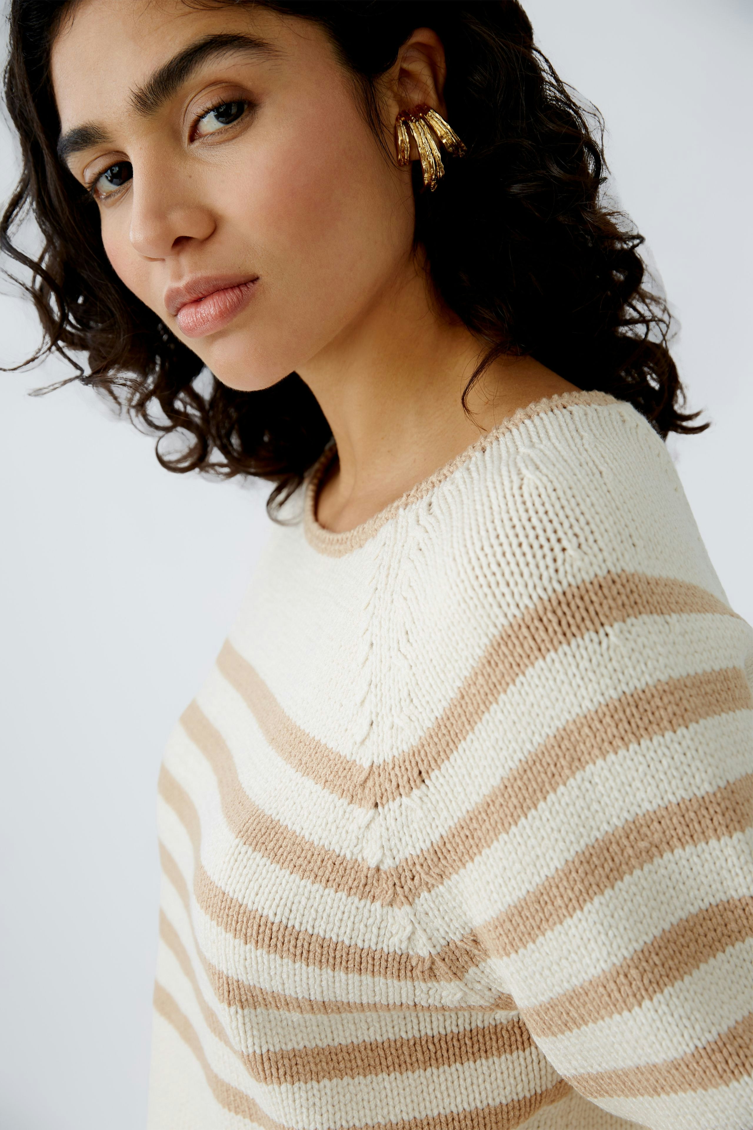 Damen-Pullover: Junge Frau in einem gestreiften Pullover in Creme und Beige mit lässigem Look.