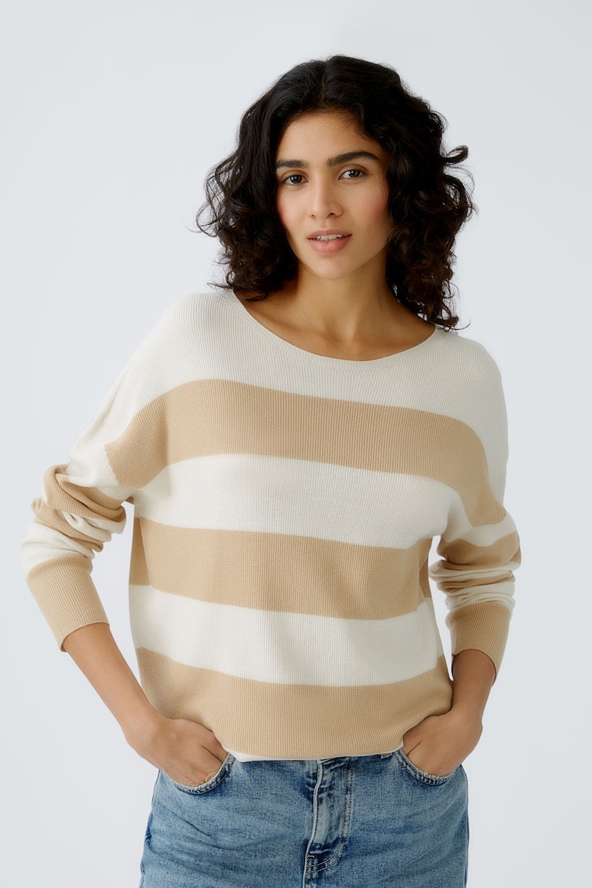 Stylish women's pullover: A woman in a beige striped pullover, exuding casual elegance.