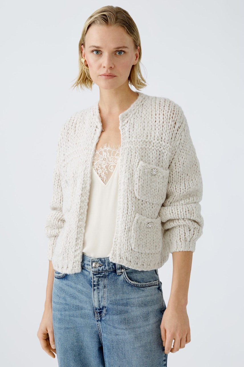 Stylish women's cardigan: A woman in a cozy, light-colored knitted cardigan with pockets.