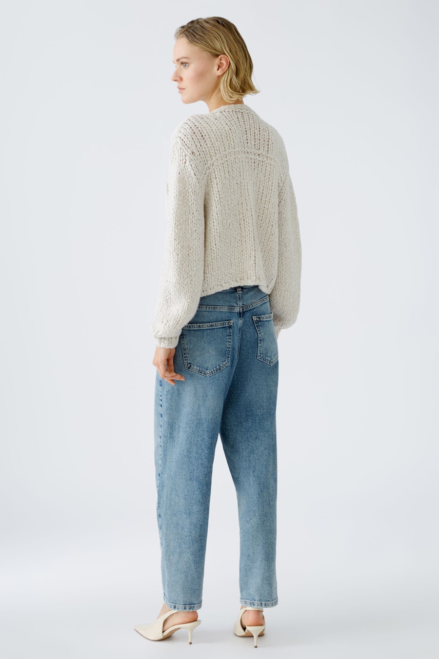 Stylish women's cardigan: A woman in a light knitted cardigan paired with relaxed jeans.